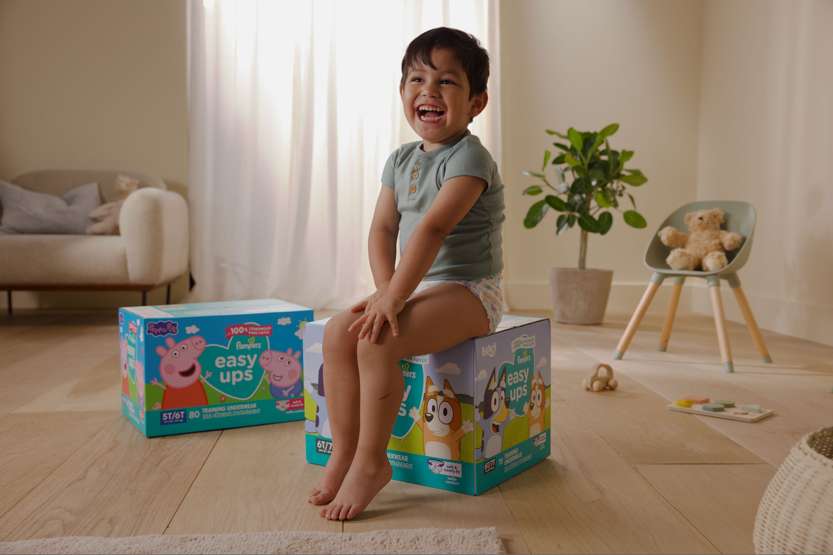 Toddler sitting on Easy Ups boxes smiling at camera