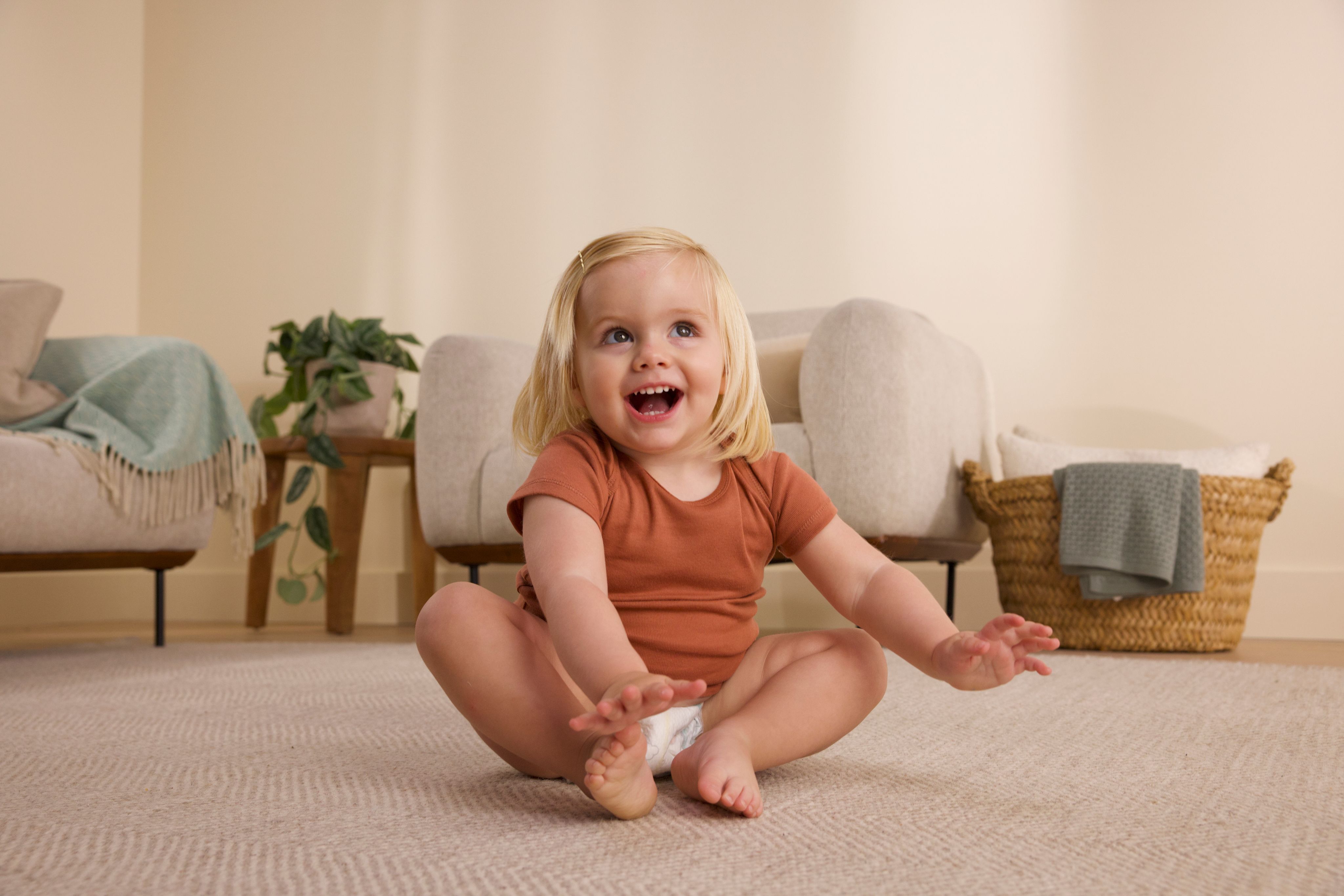 Toddler sitting on floor laughing