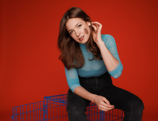 Portrait of a comedian seated against a red backdrop