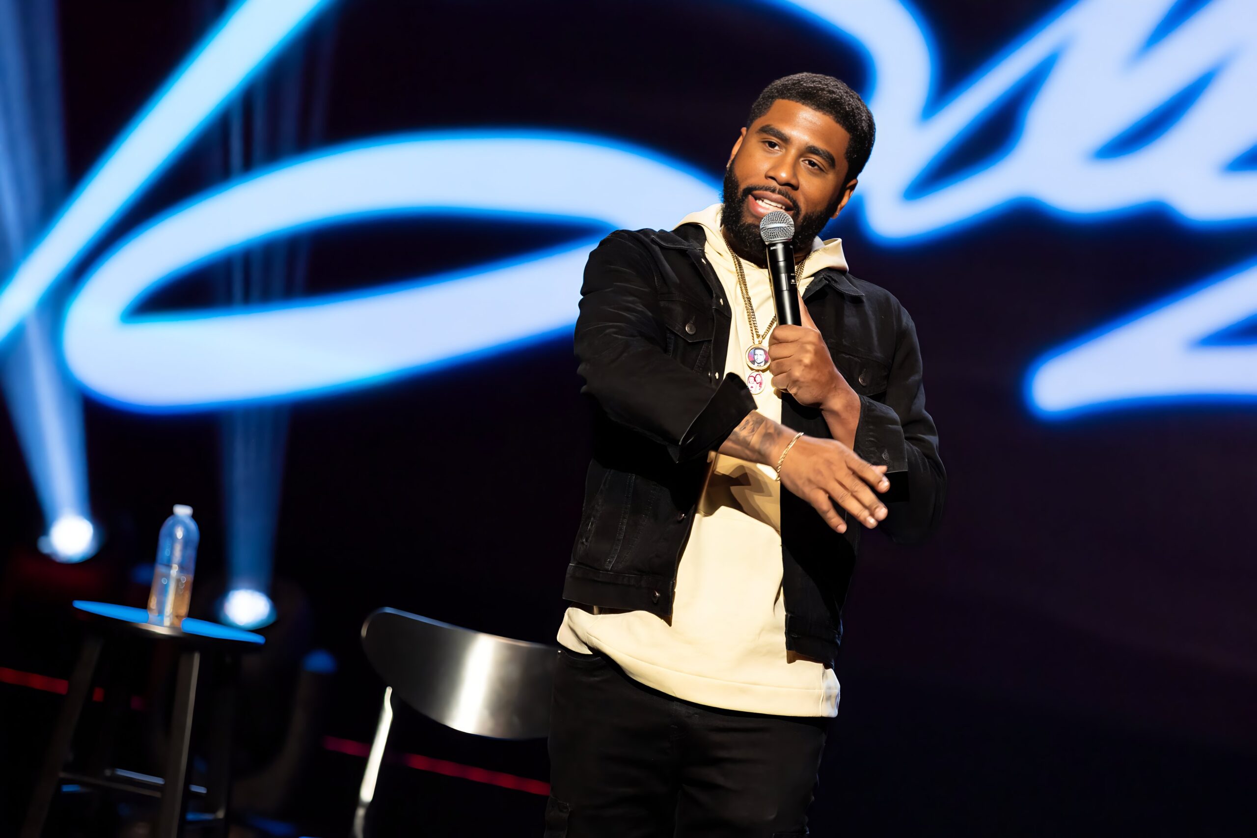 A comedian performing stand-up under blue stage lights