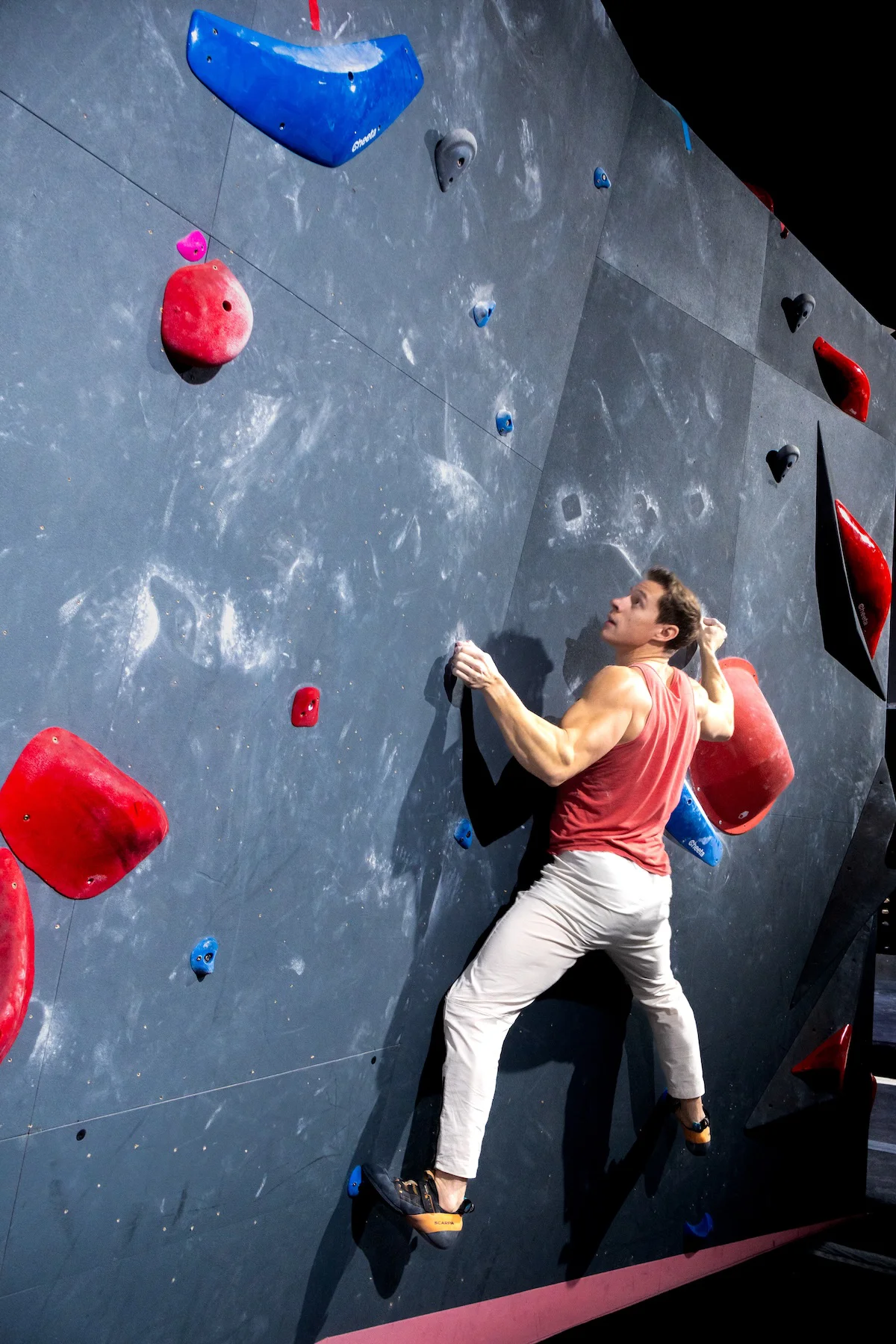 Climber bouldering up a vertical wall on colorful holds at Shift Climbing indoor bouldering gym