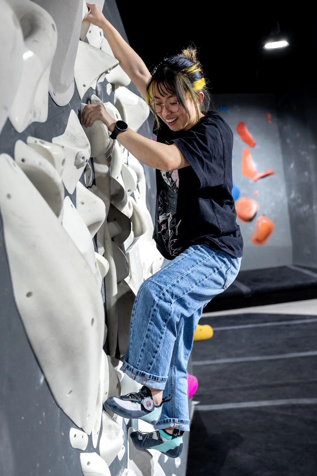 Climber bouldering on a steep textured wall of white volumes at Shift Climbing indoor gym