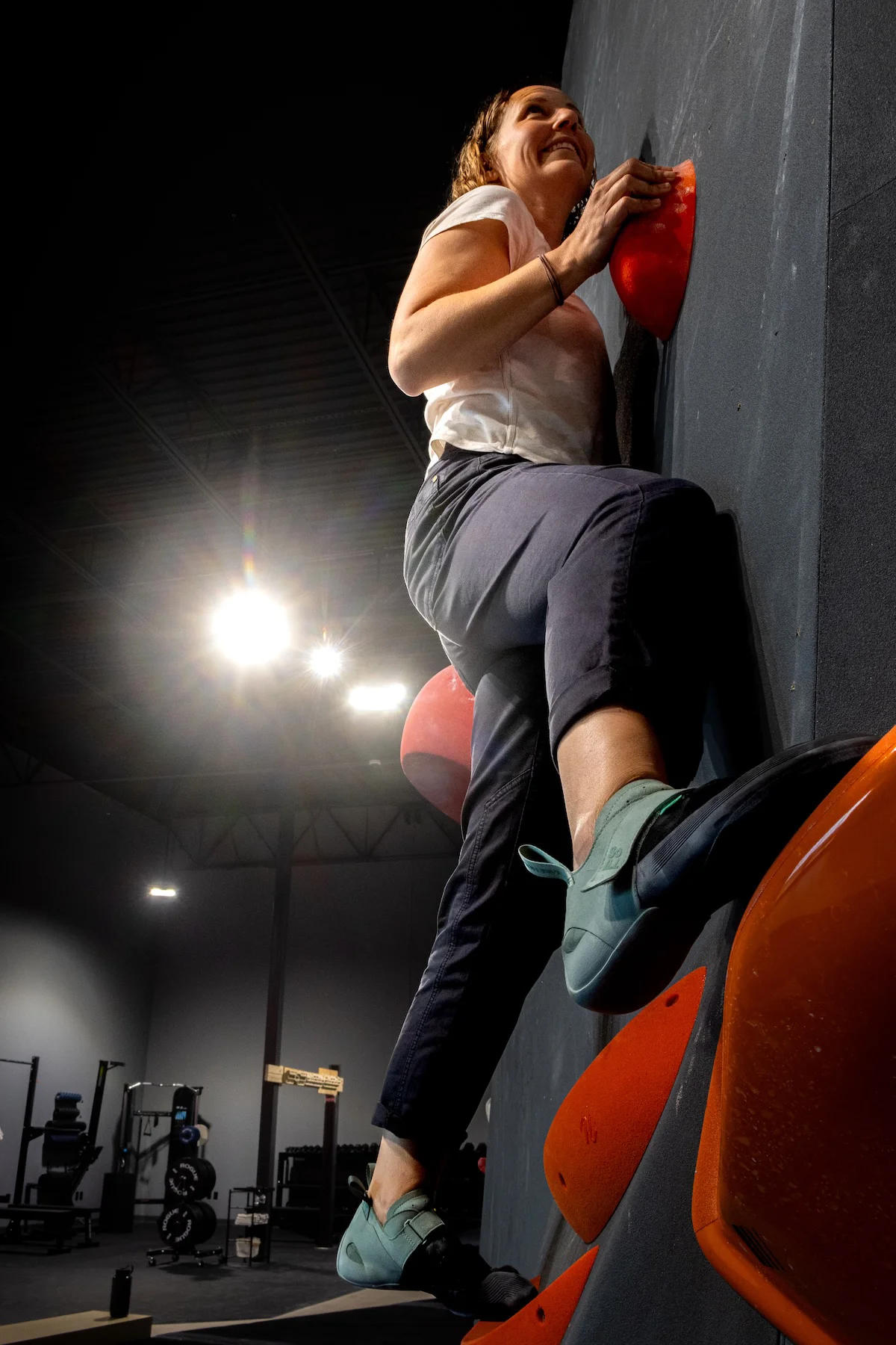 Low-angle view of a woman bouldering on an overhanging climbing wall at Shift Climbing gym