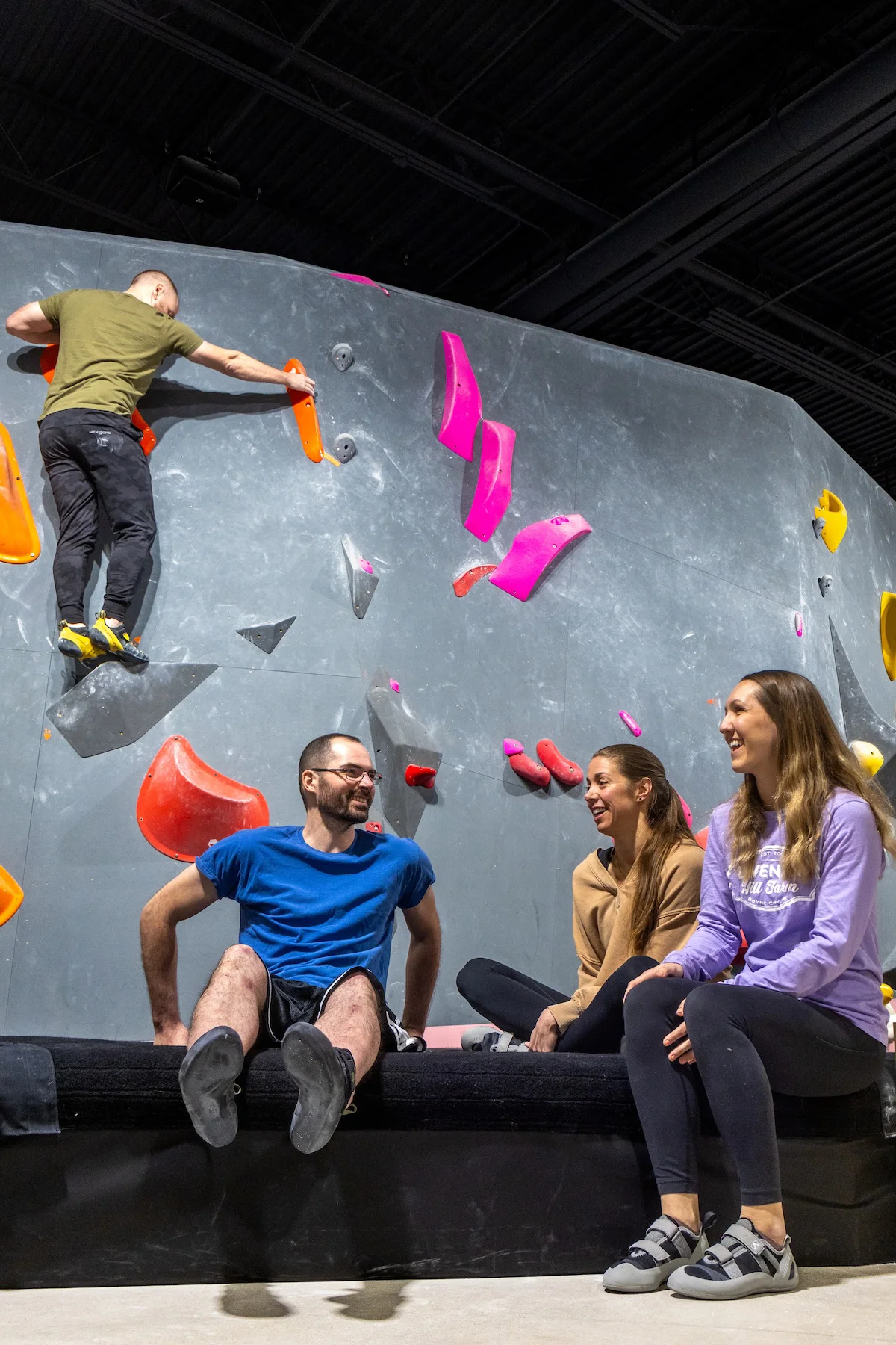 Friends relaxing and socializing beside the bouldering wall at Shift Climbing community gym