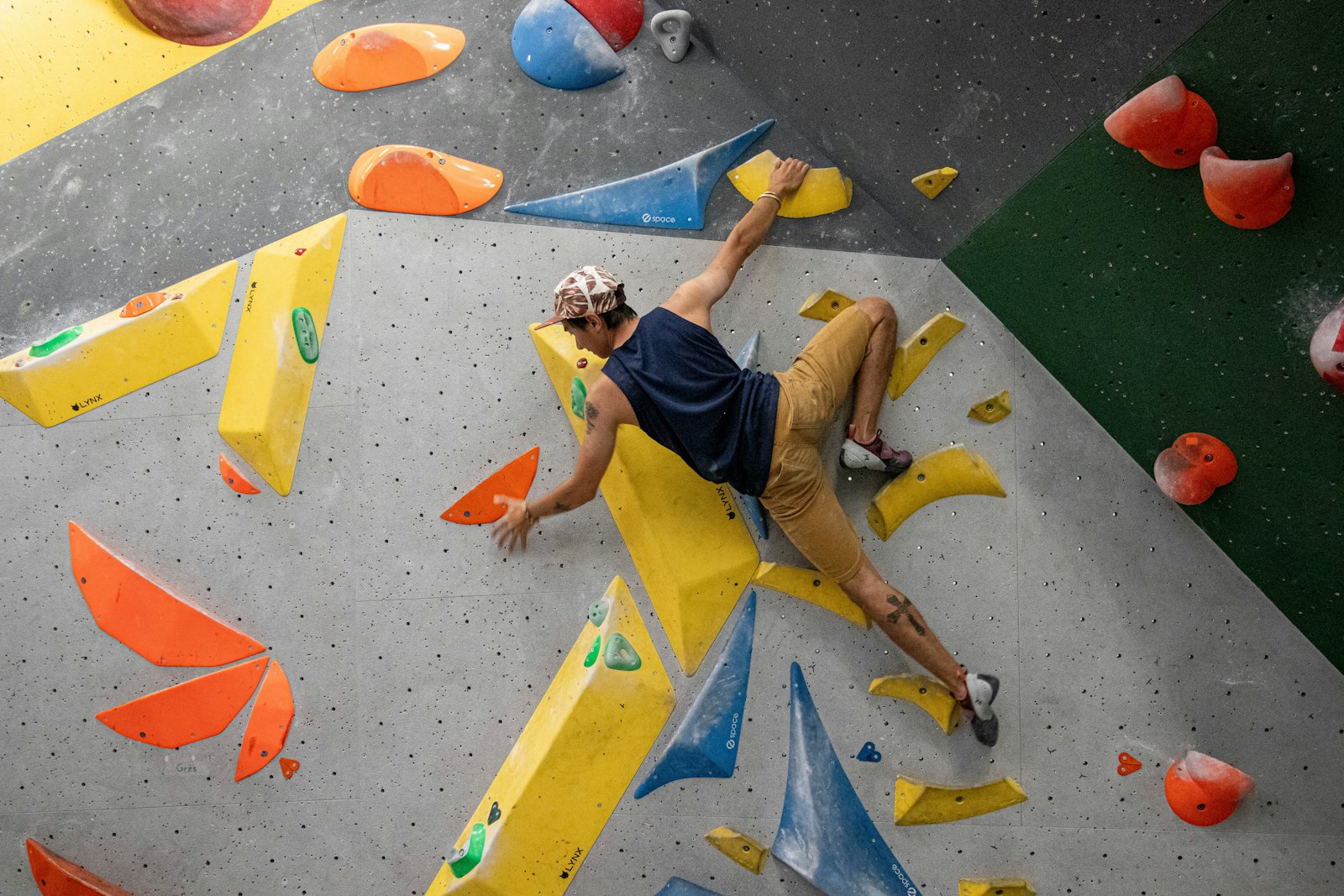 A single climber working a boulder problem on an indoor climbing wall