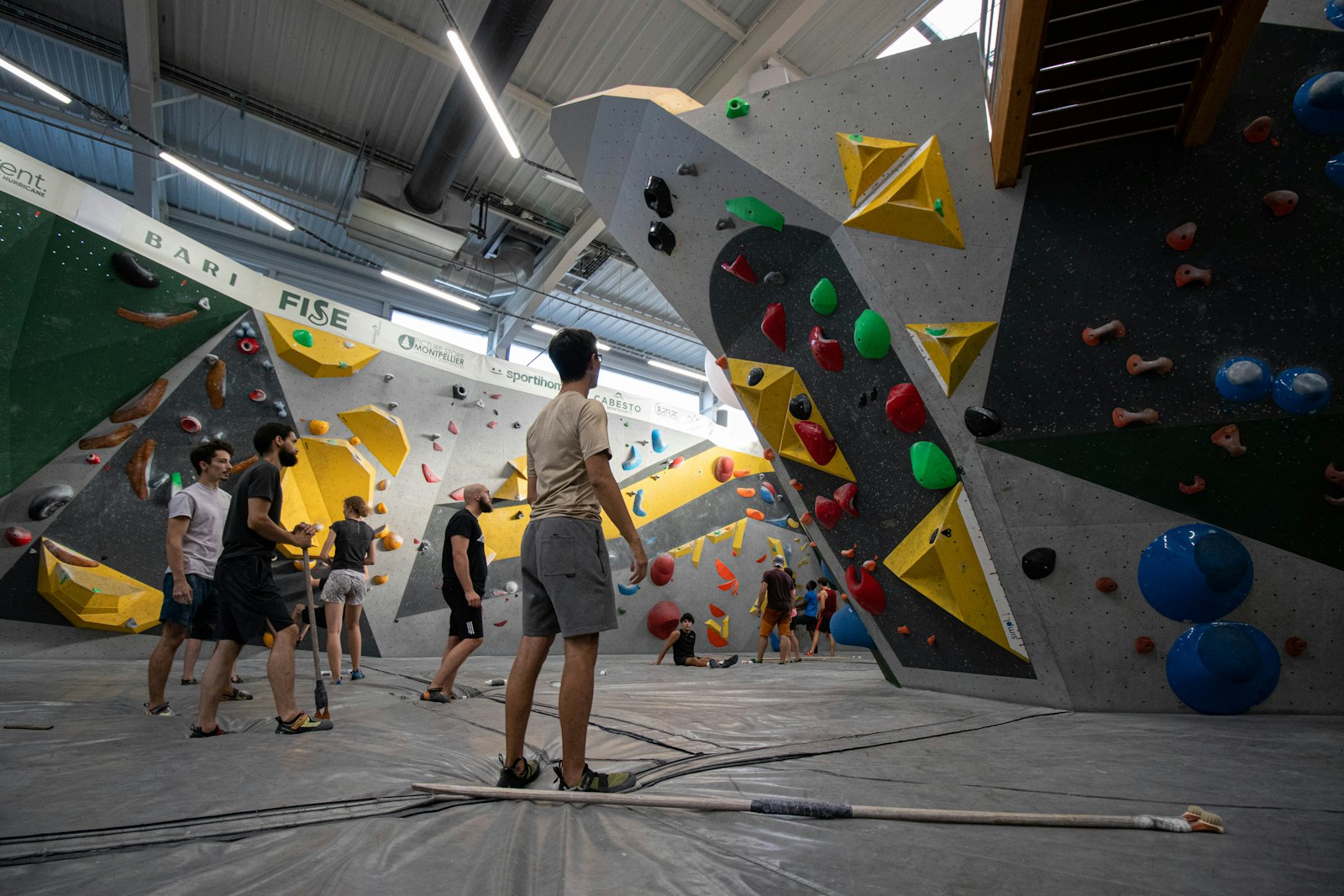 A group of people standing around a bouldering wall at a climbing gym