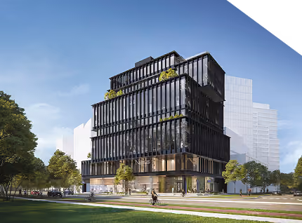 Modern black glass office building with trees and lawn in front under blue sky.