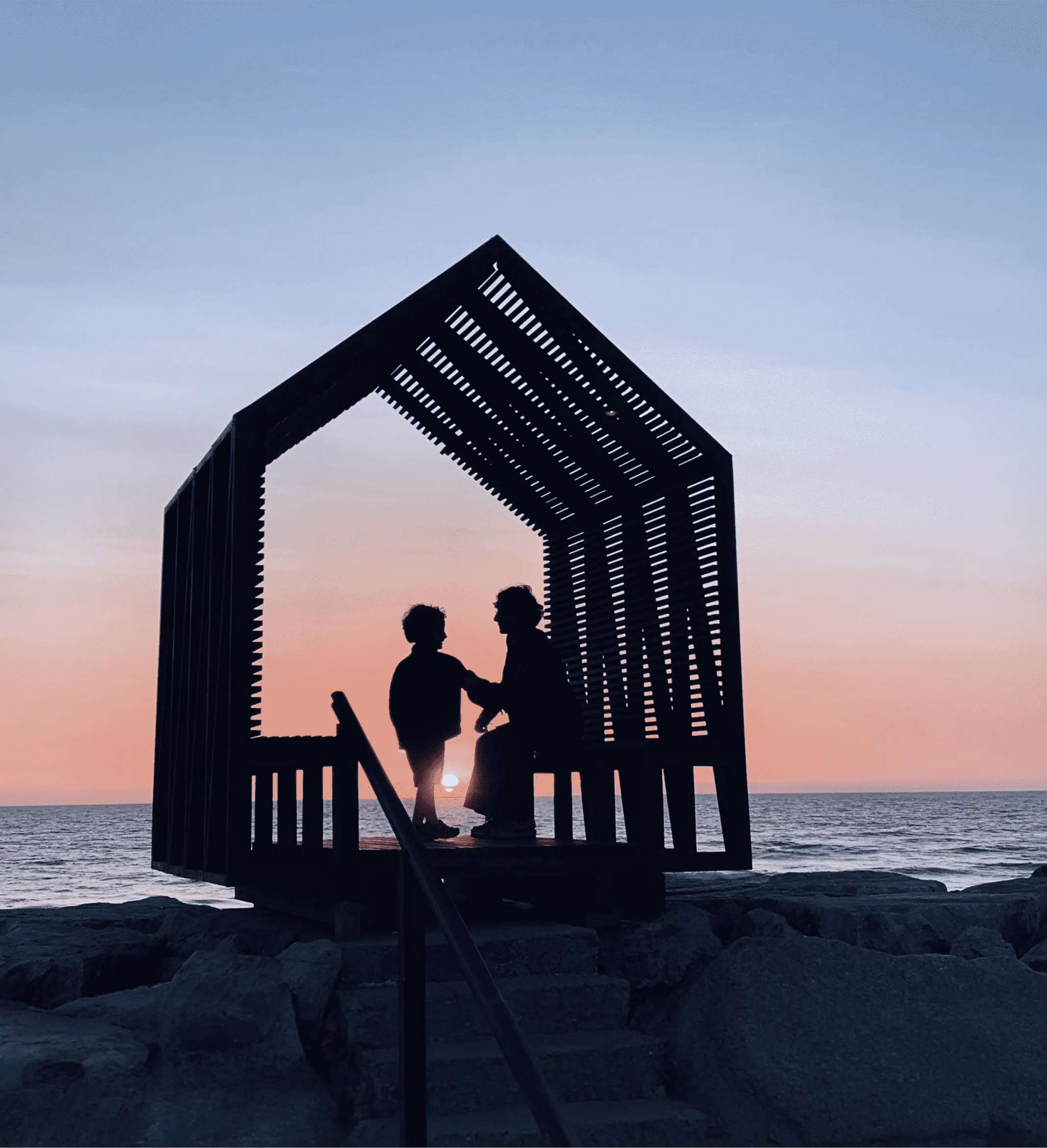 Silueta de madre e hijo bajo un techo al atardecer, representando protección y seguridad con seguros de Betterplan