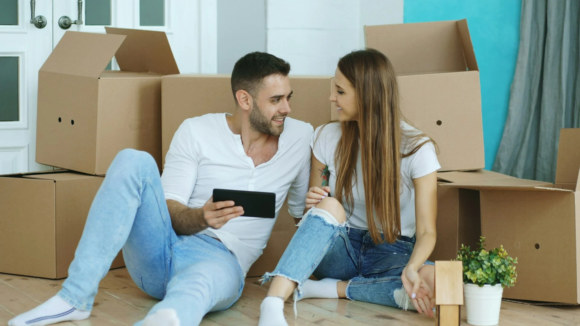 couple sittin among boxes and preparing for moving for the first time