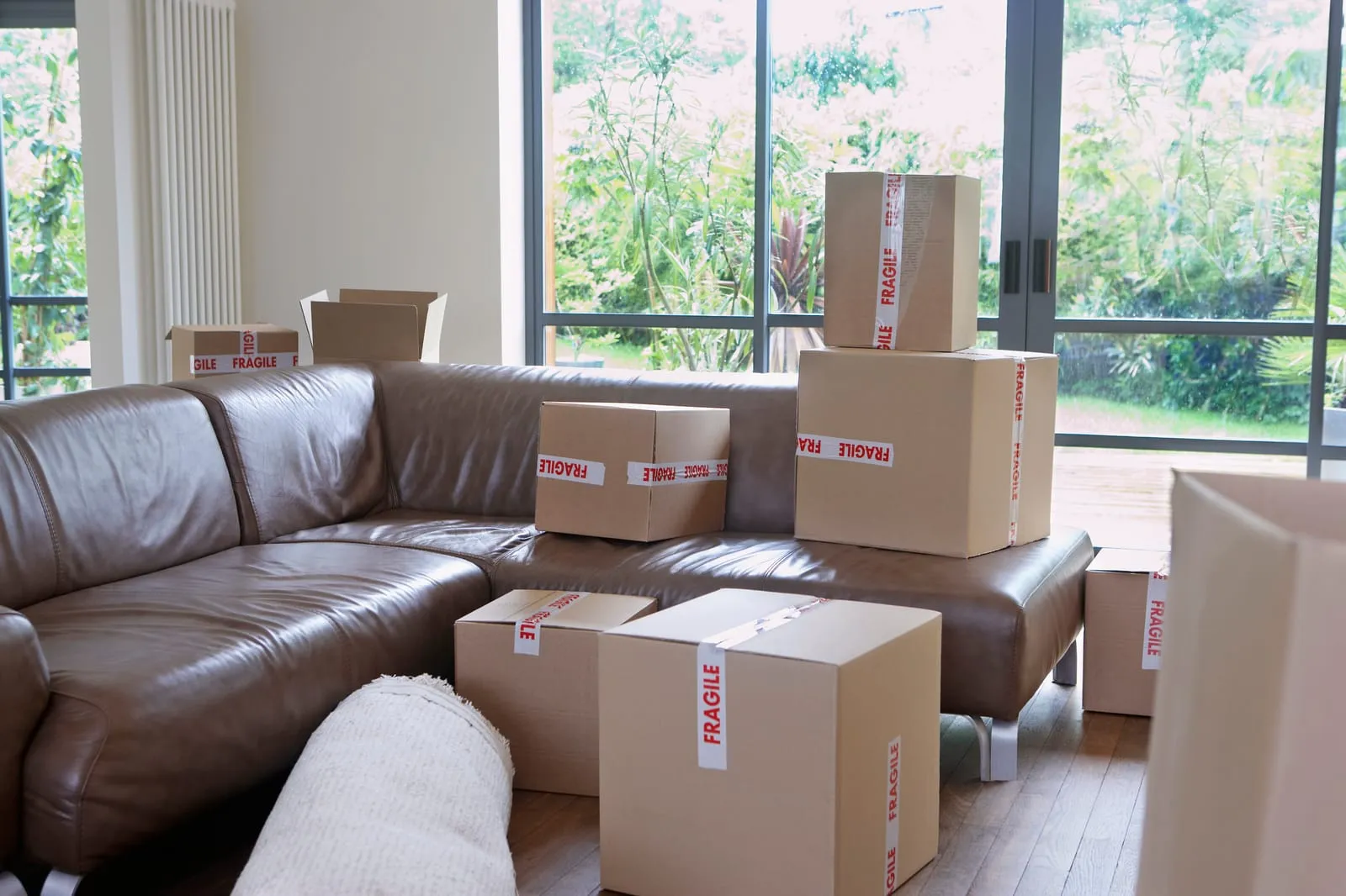 Cardboard boxes labeled fragile organized on a sofa, demonstrating DIY packing to save money when moving.