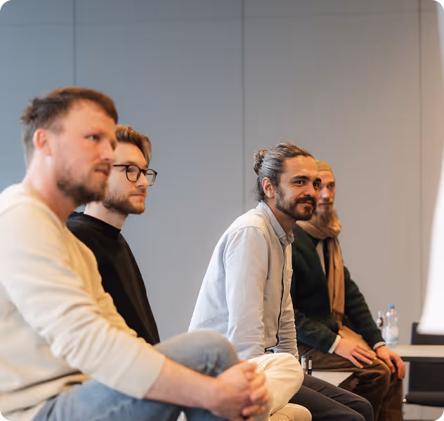 Fotos von Personen mit ihren Computern an einem Tisch, die sich lächelnd unterhalten