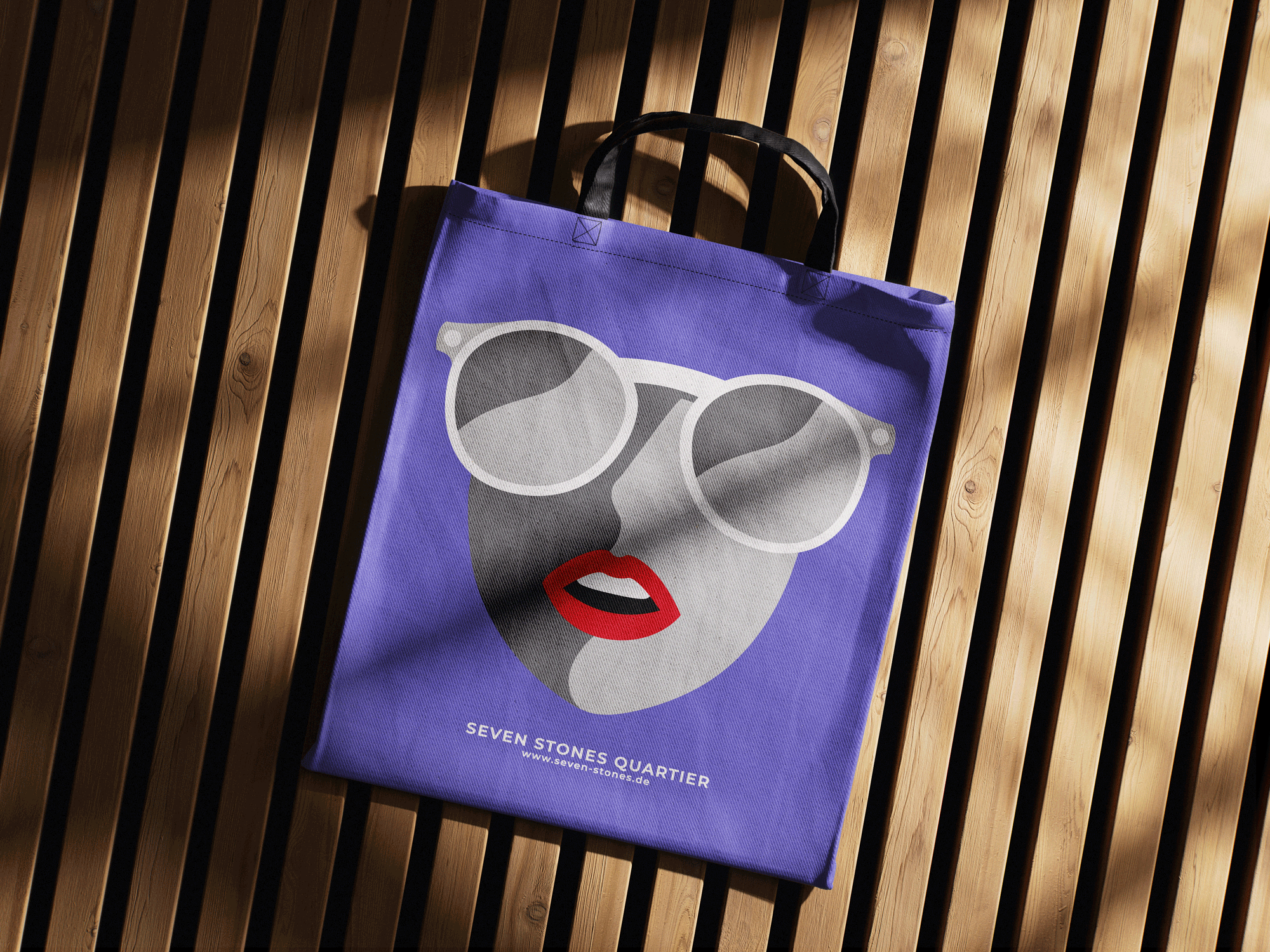 Lila Einkaufstasche mit Gesicht in Sonnenbrille und roten Lippen, liegt auf Holzlattenboden.