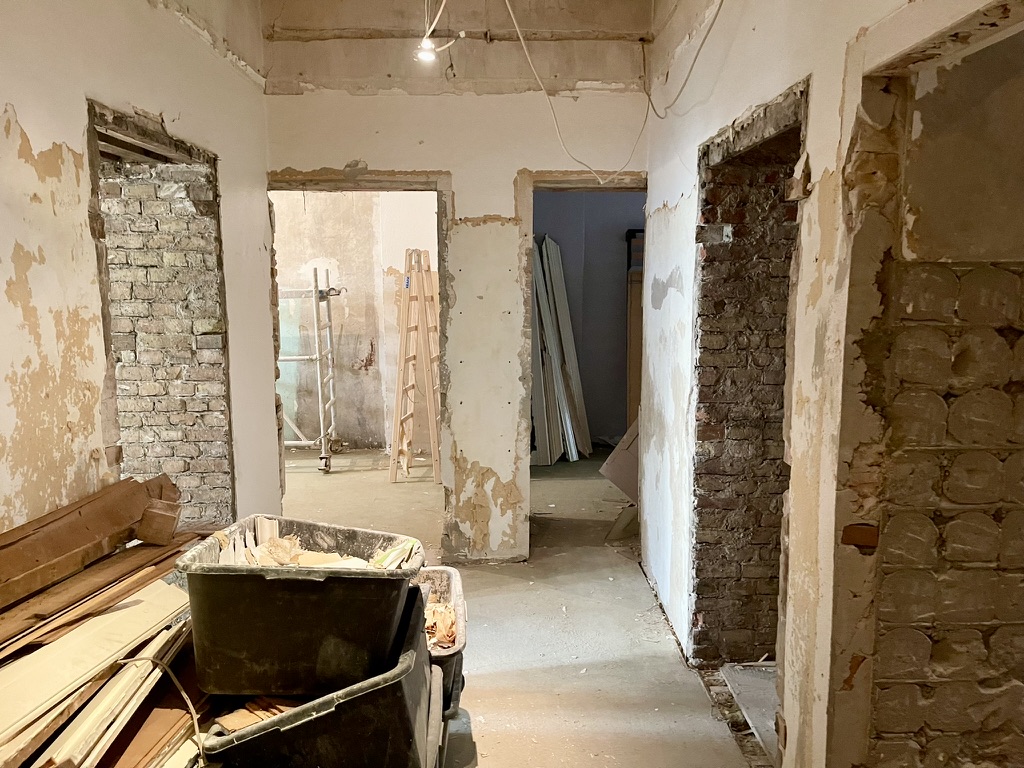 Rohbau-Innenraum mit freiliegenden Ziegelwänden, Werkzeug und Baumaterialien auf dem Boden.