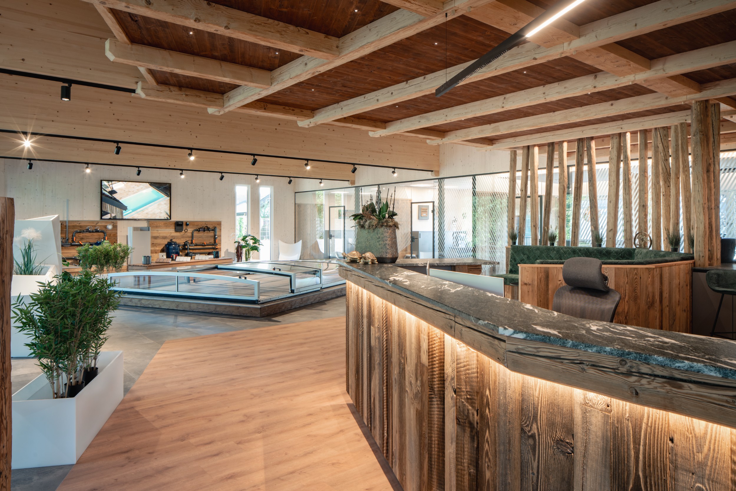 Moderne Rezeption mit Holzverkleidung, Marmor-Theke und Pflanzen in einem hellen, offenen Raum mit Holzdecke und Sitzbereich.