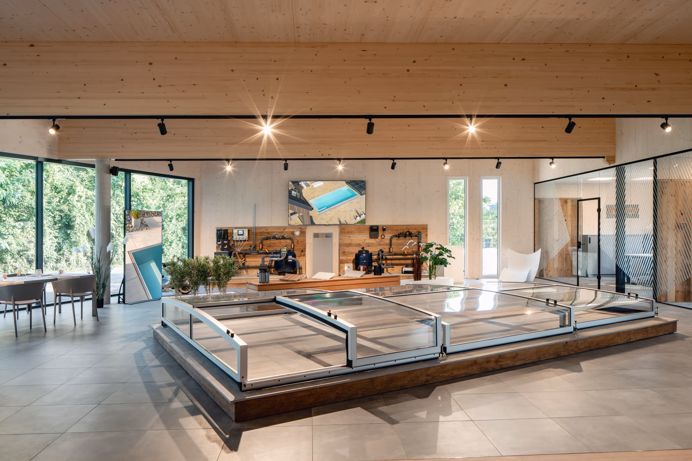 Moderner Ausstellungsraum mit einer abgedeckten Schwimmbeckeninstallation, großen Fenstern und minimalistischer Einrichtung.