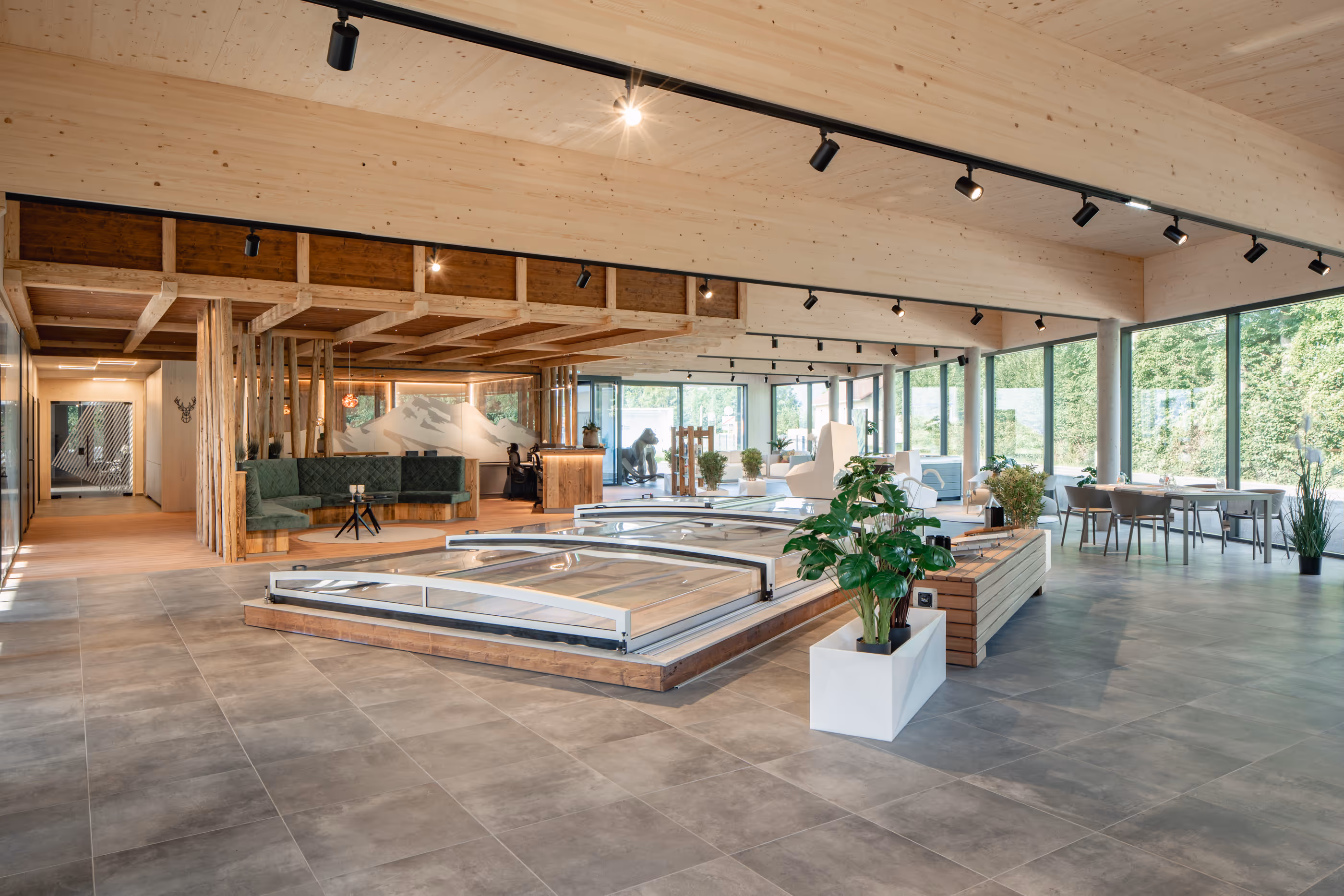 Offener moderner Schauraum mit großen Fenstern, Bepflanzung und Sitzgelegenheiten.