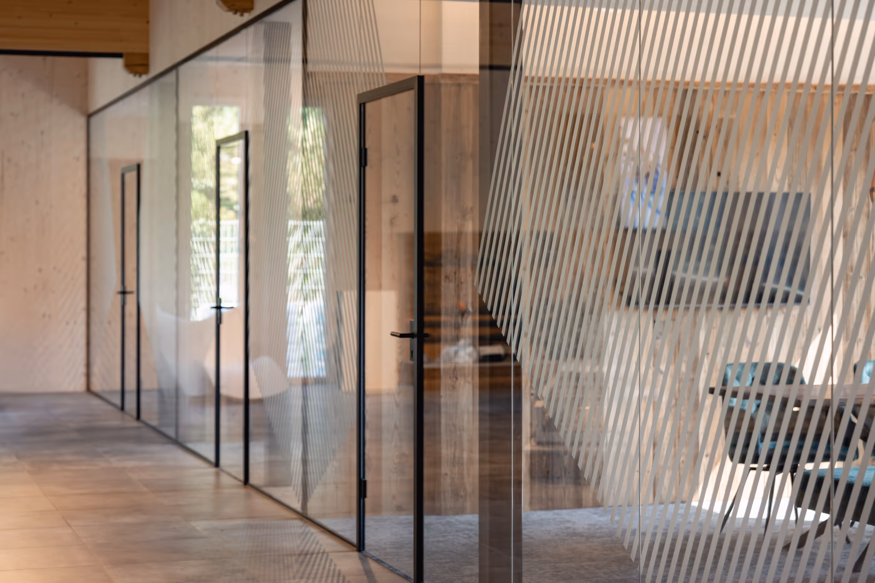 Moderner Flur mit Glaswänden und Holzdecke, Büroeinrichtung mit Sitzgruppen und Monitoren.