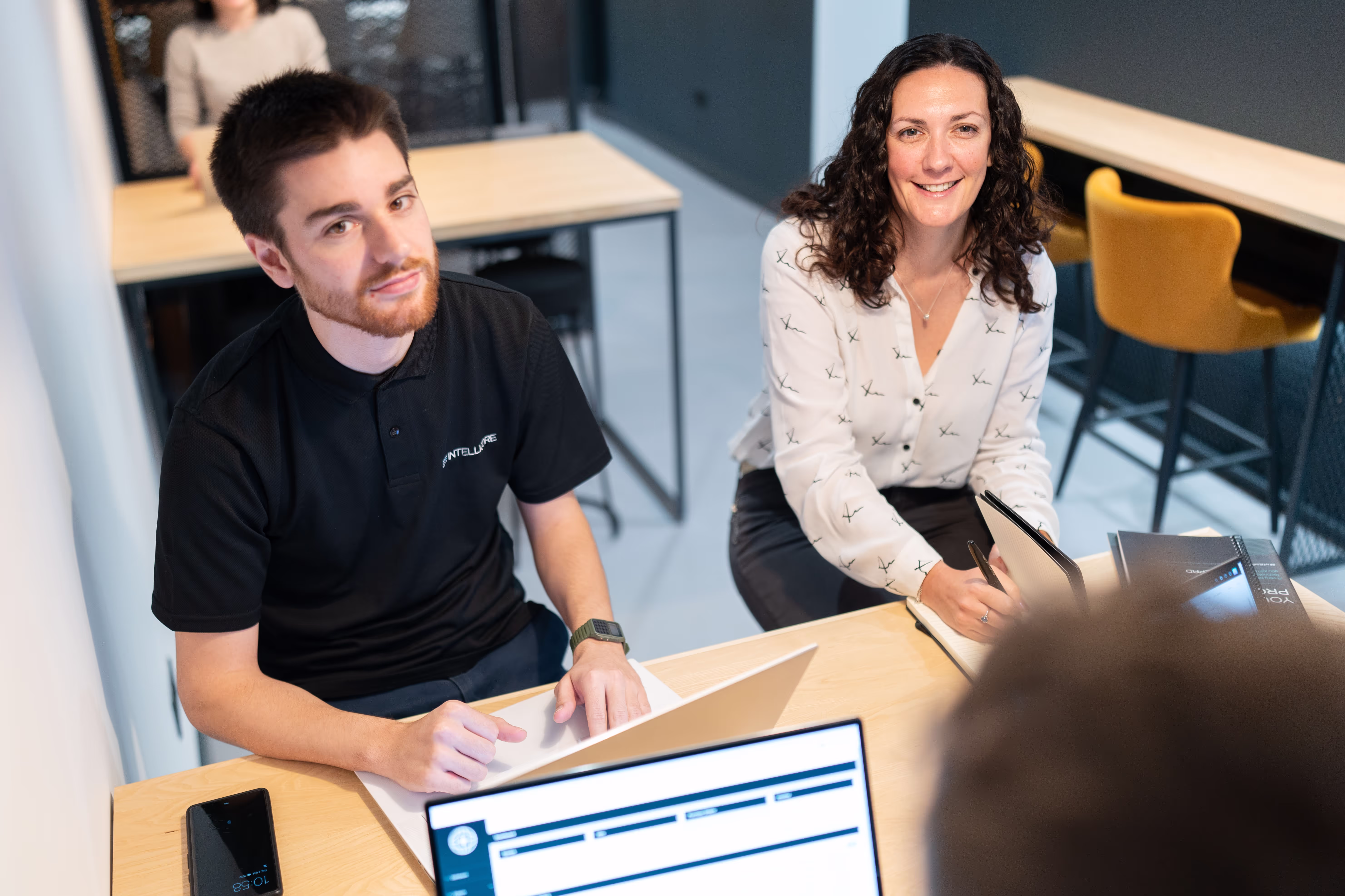 A photo of employees in the Intellicore Office smiling and collaborating with each other