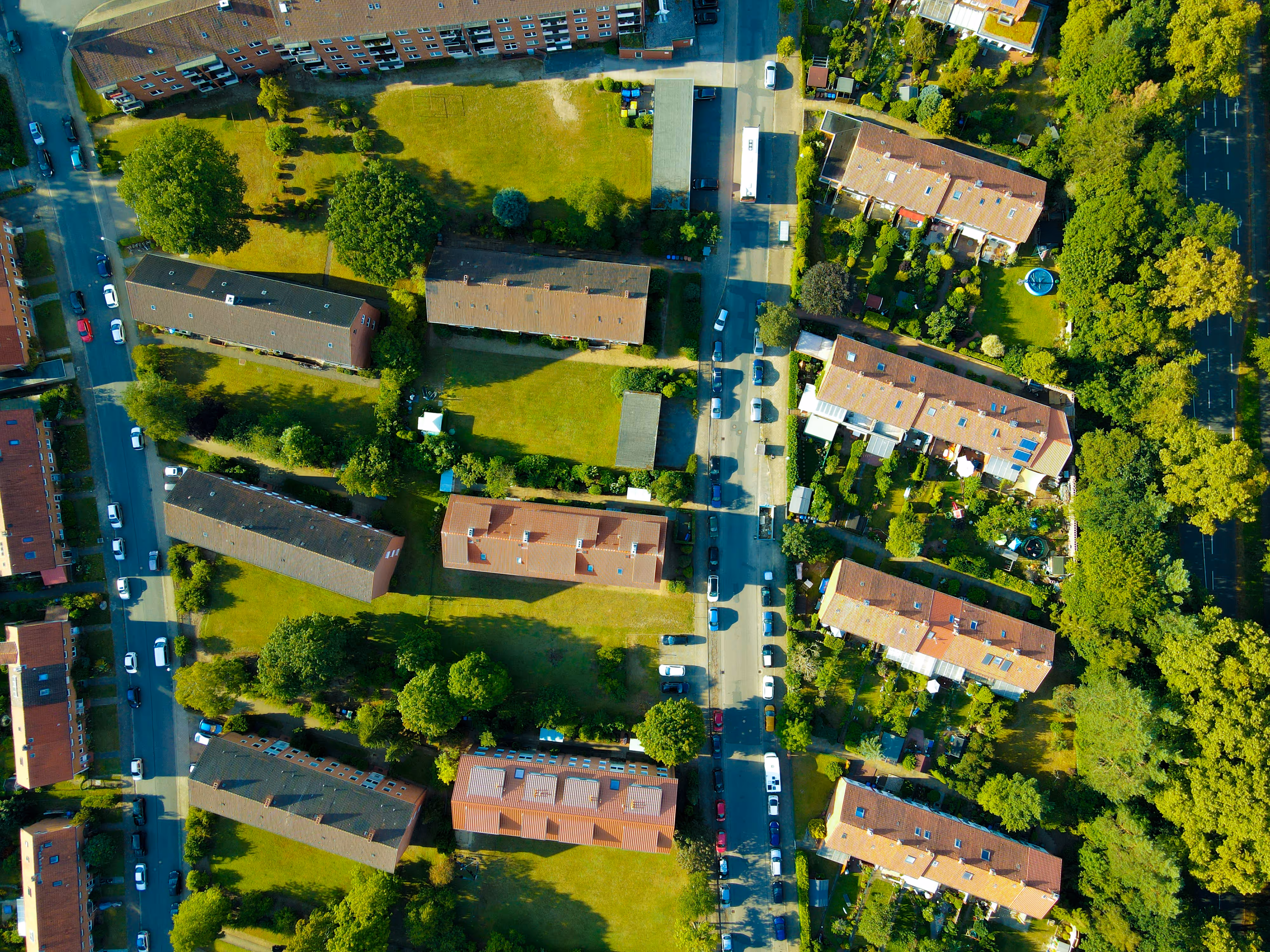 Vue aérienne d'un quartier résidentiel avec des immeubles, des pelouses vertes et des arbres.