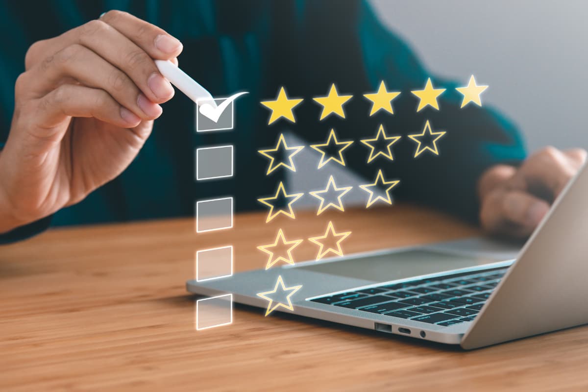 Hand setzt digitalen Haken in eine Checkliste, daneben fünf gelbe Sterne zur Bewertung – Symbol für Patientenzufriedenheit.