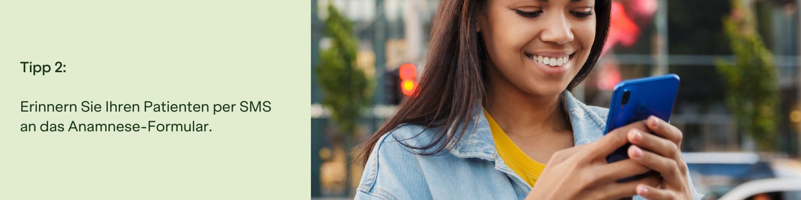 Junge Frau liest lächelnd eine Nachricht auf ihrem Smartphone im urbanen Umfeld.