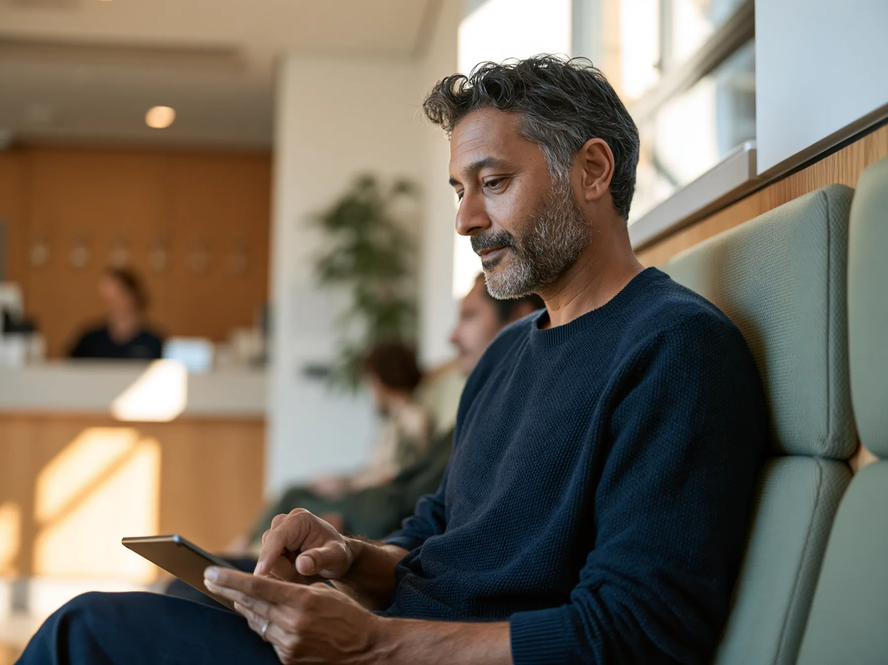 Patient sitting in the waiting area of a dental practice filling out the medical history form on a tablet
