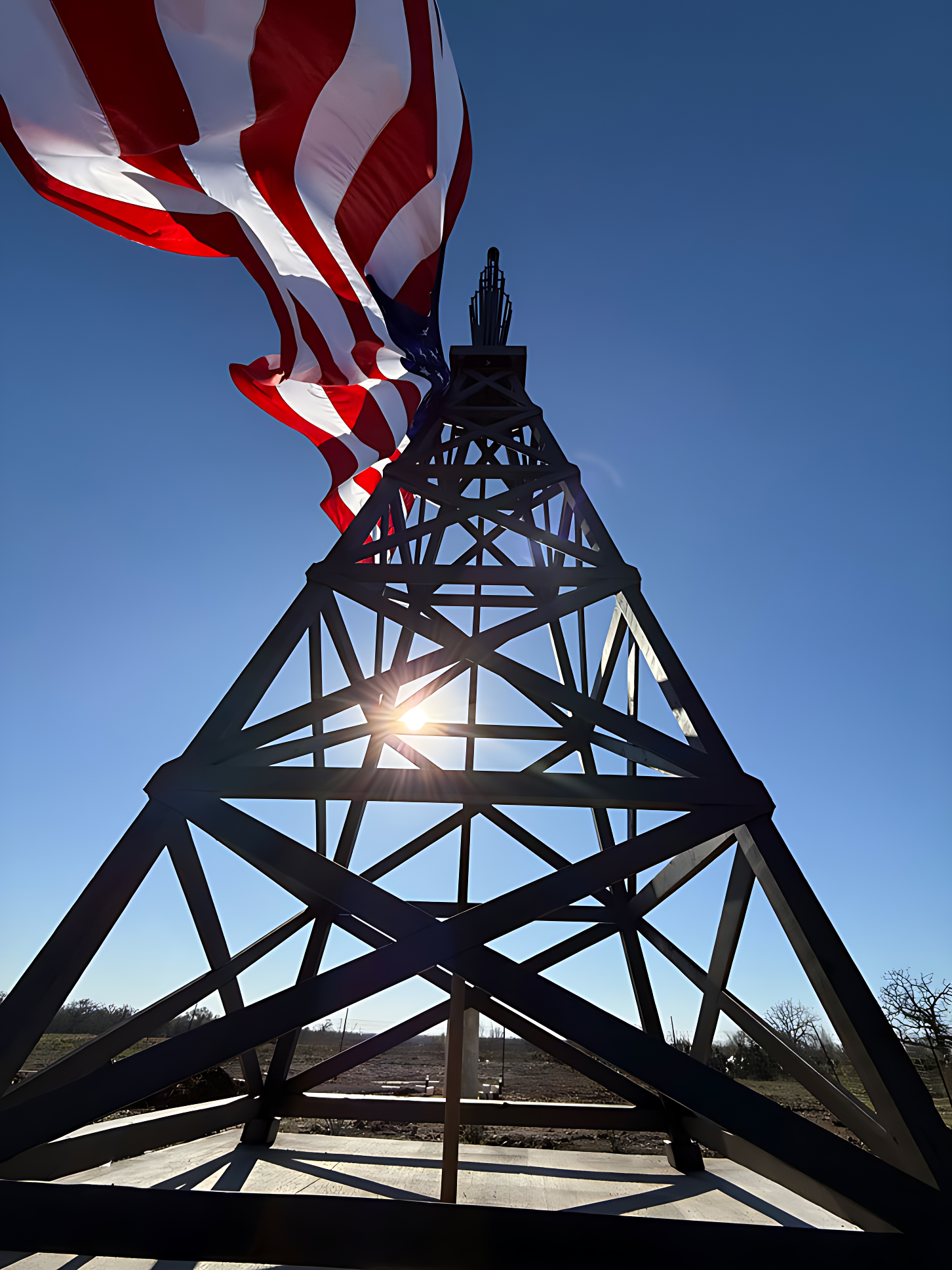 Spindletop perspective from its base looking up, with a large flag of USA adorning the monument