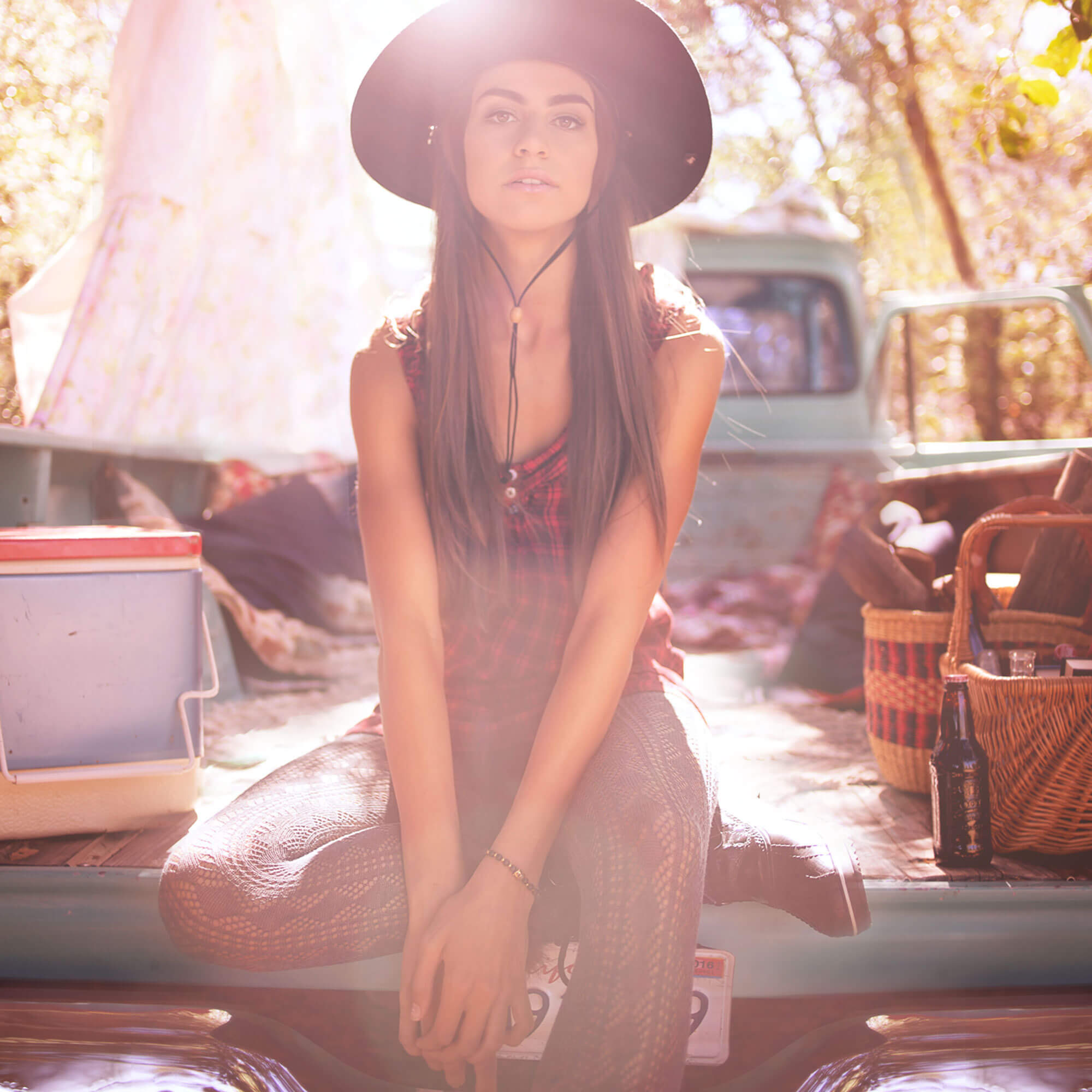 Fashionable women sitting in the bed of an old pickup truck.