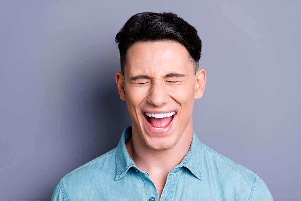 A man laughing with his eyes closed.