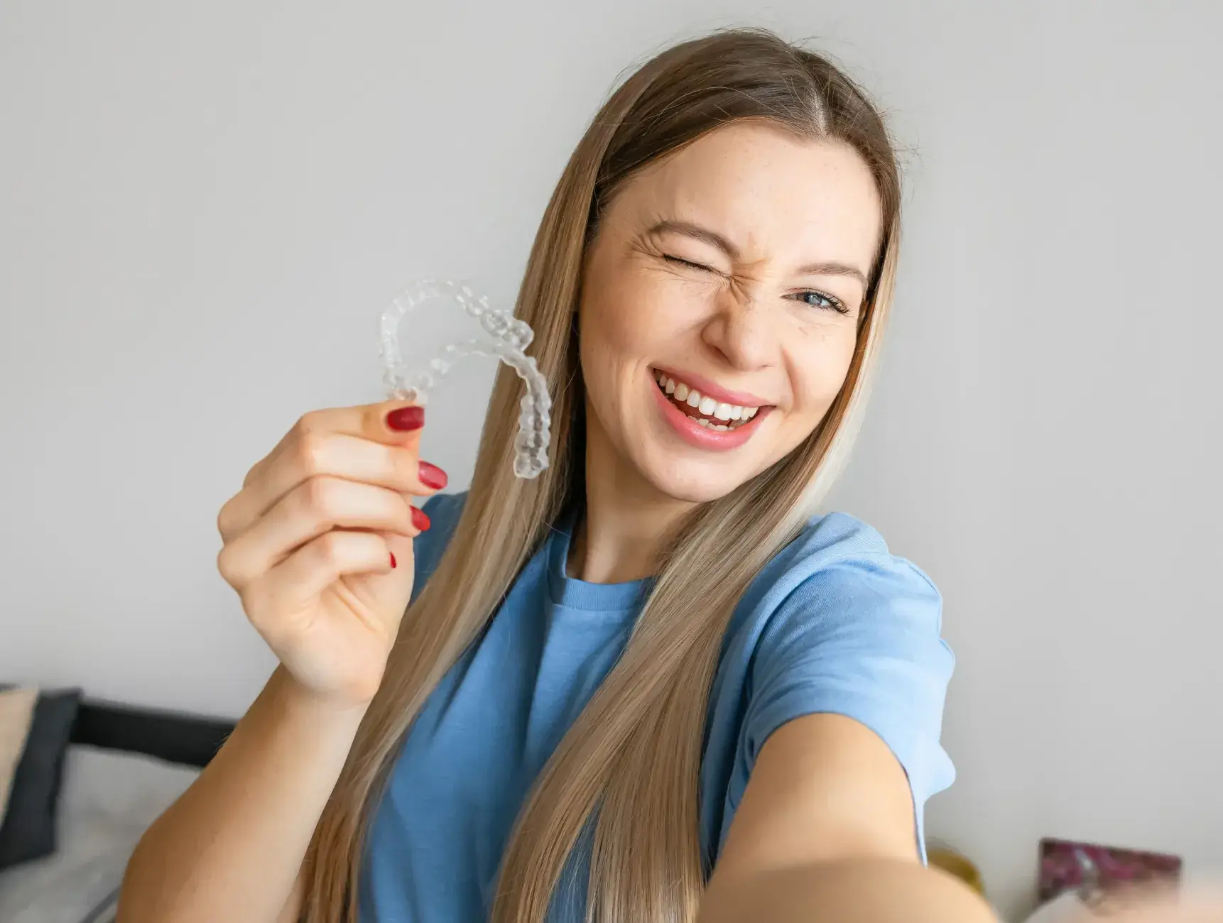 A woman smiles while holding a clear toothbrush.