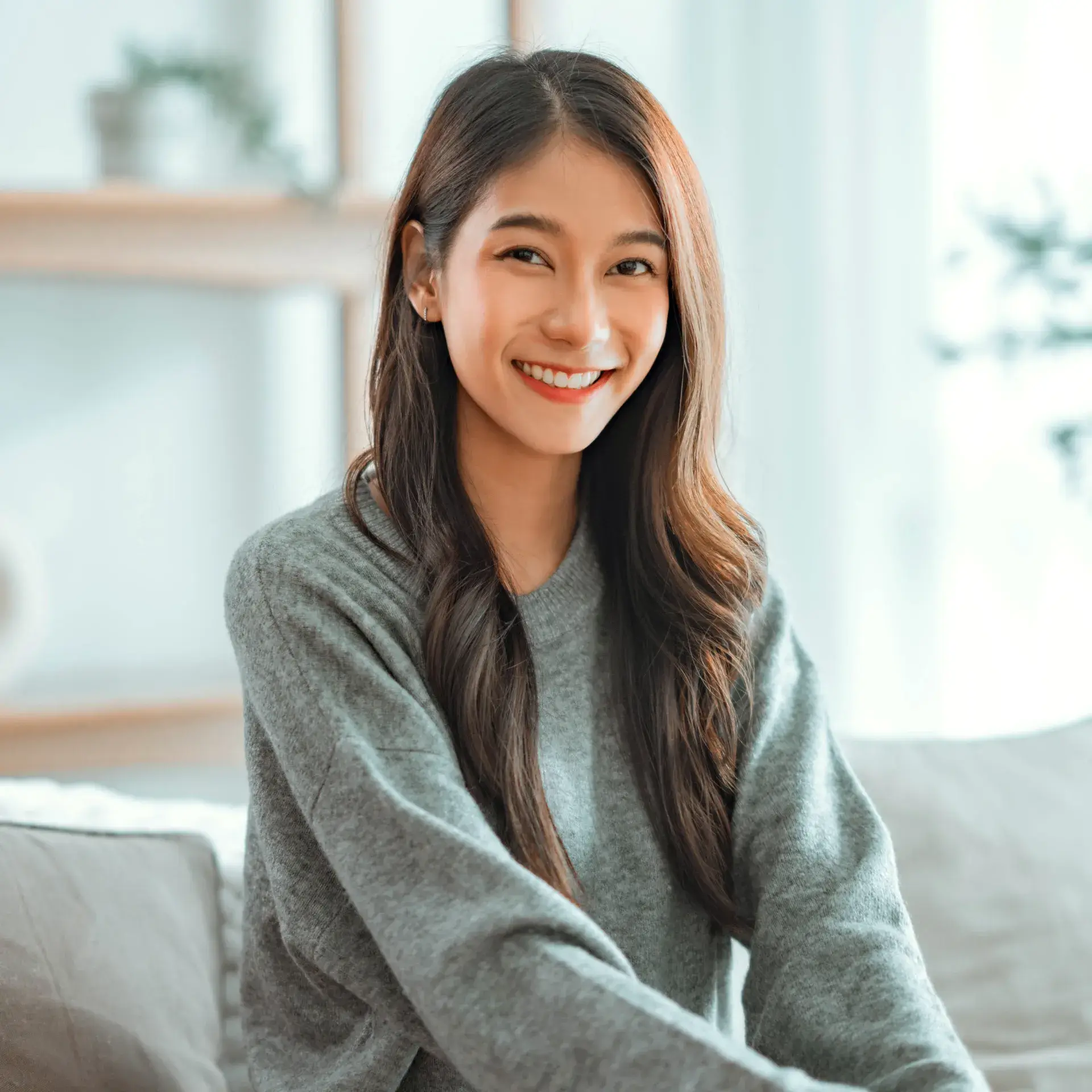 A woman sitting on a couch smiling at the camera.