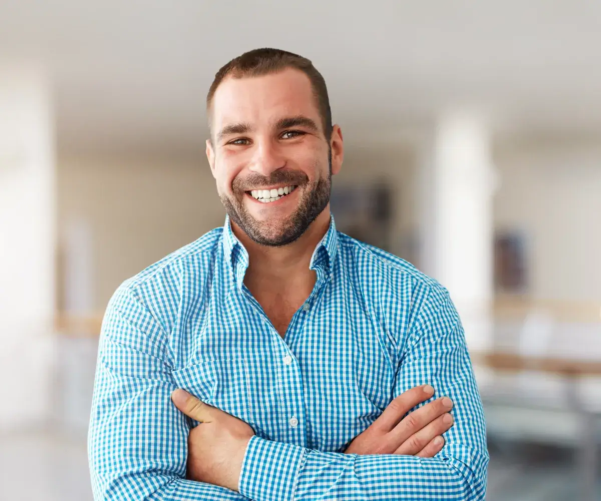 A man with his arms crossed smiling.