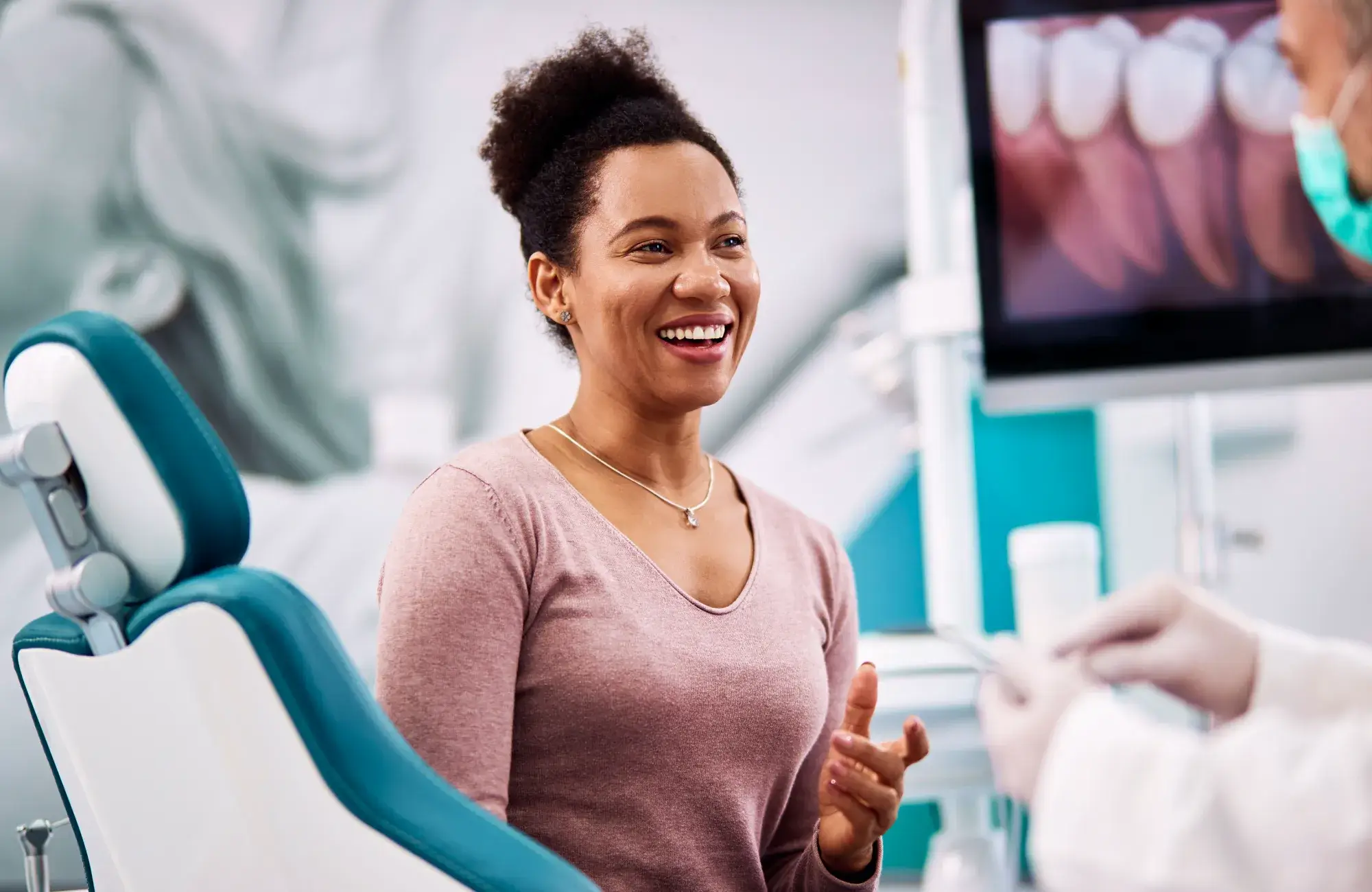 A woman smiles as she sits in a dental chair.