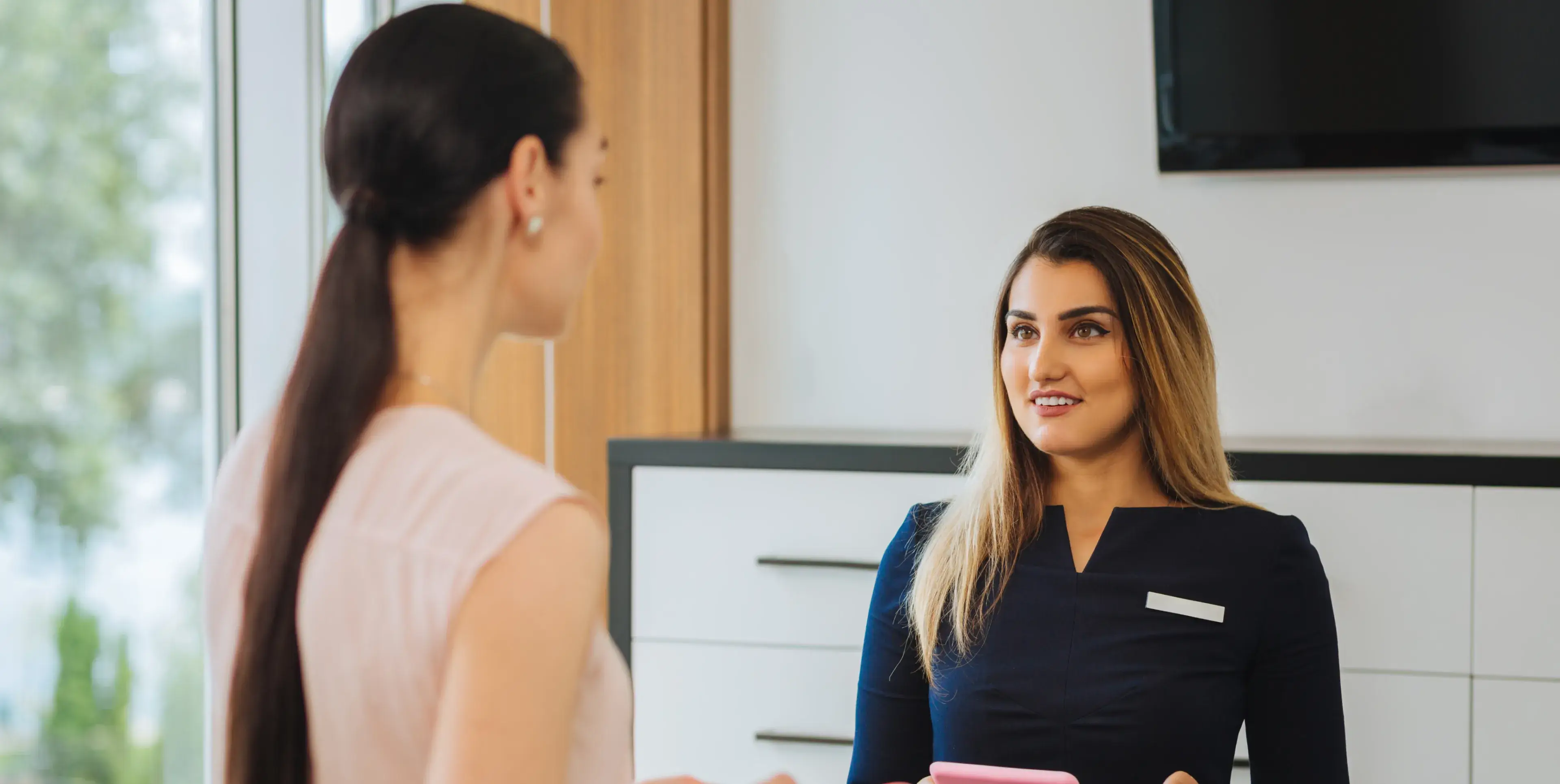 A woman talking to another woman in a room.