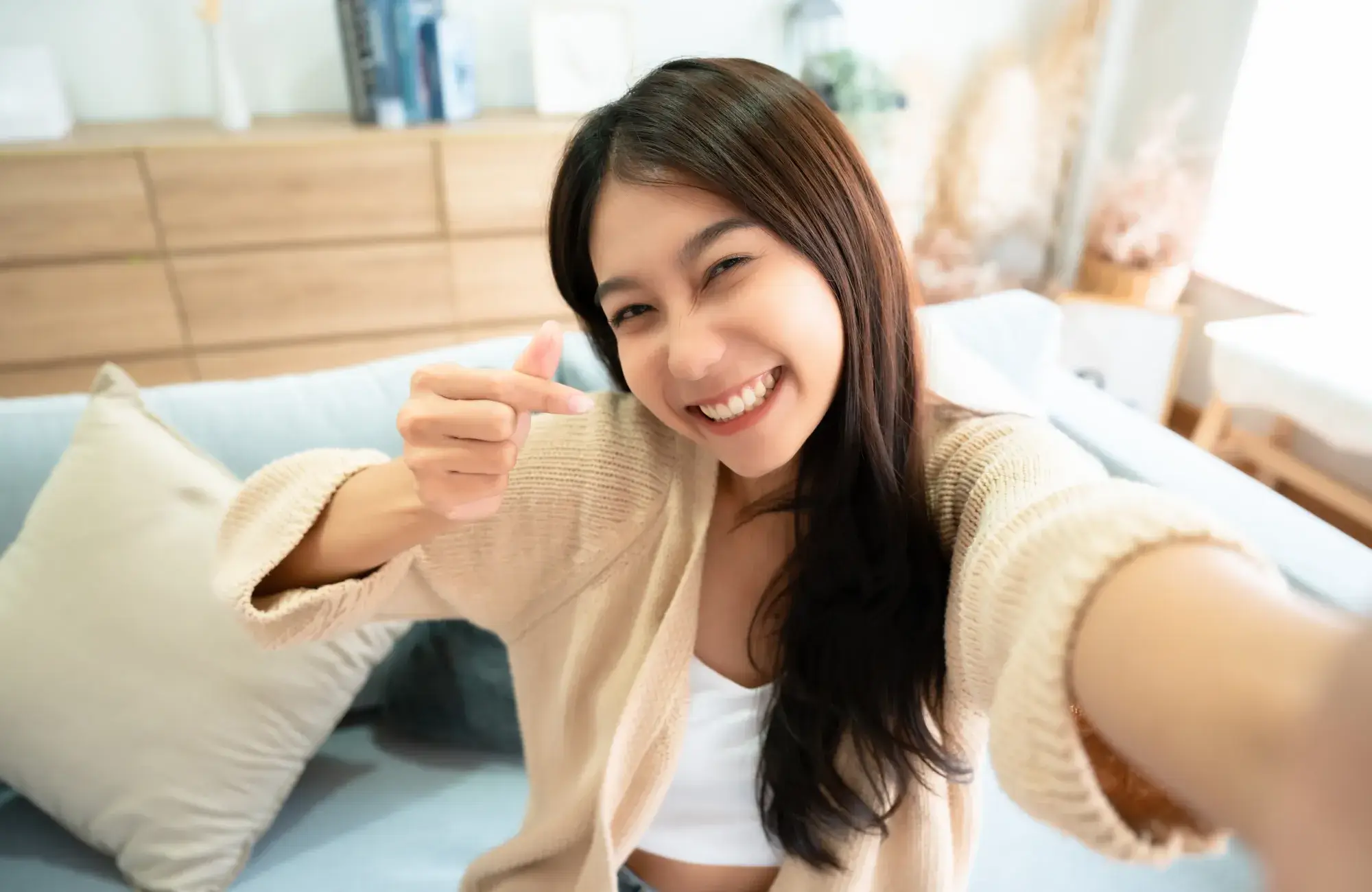 A woman pointing at the camera with a smile on her face.