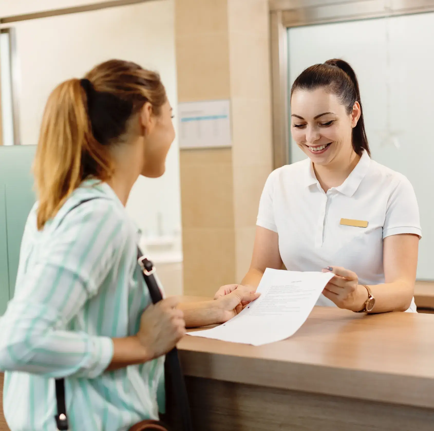 A woman sitting at a desk with a woman standing next to her.