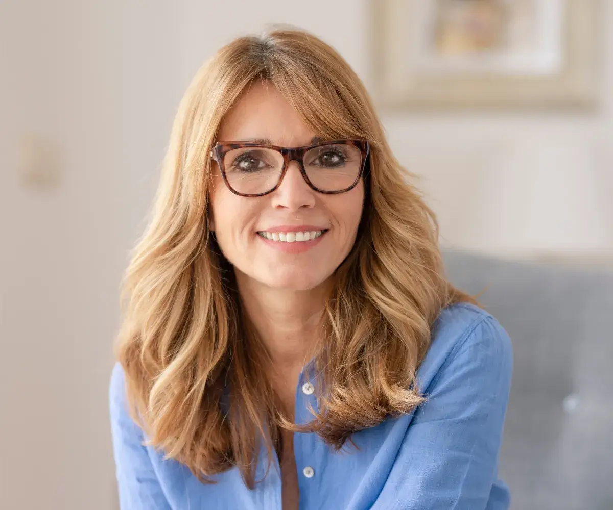 A woman wearing glasses sitting on a couch.