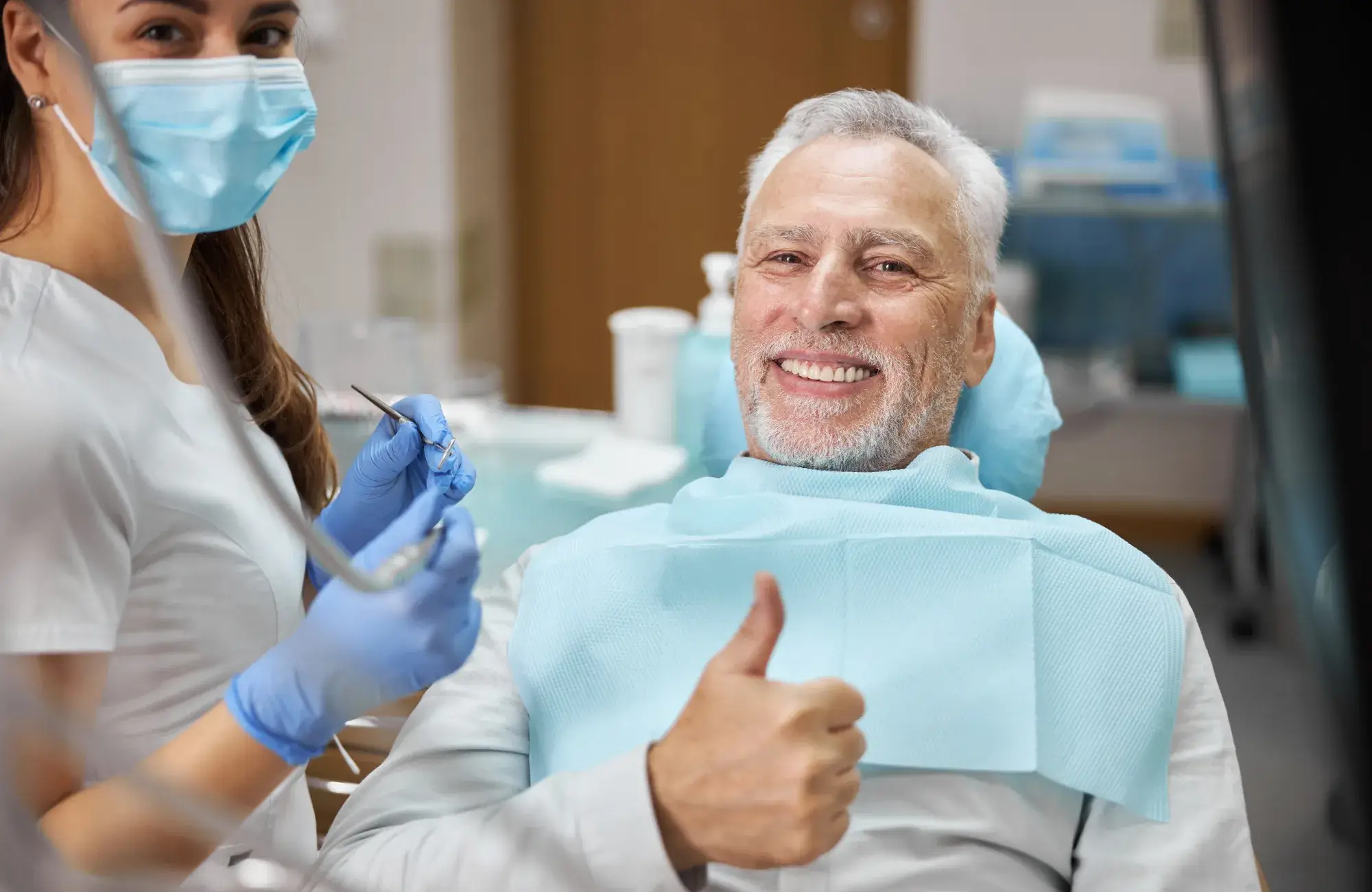 A man in a dentist chair giving a thumbs up.