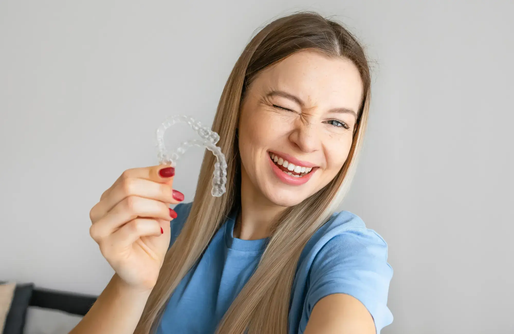 A woman holding a clear toothbrush in her right hand.