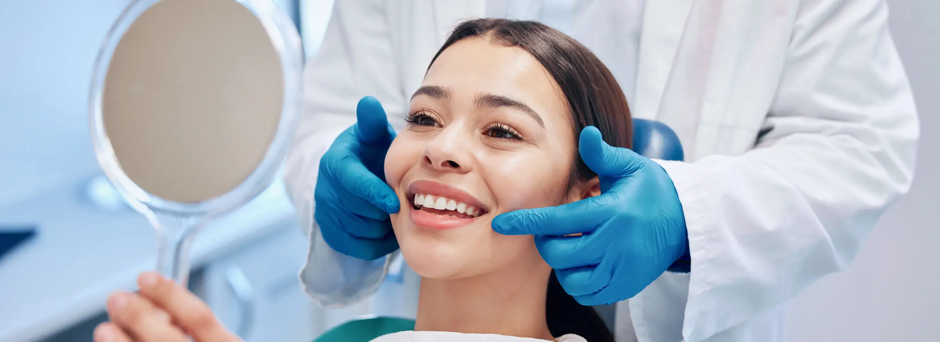 A woman getting her teeth brushed by a dentist.