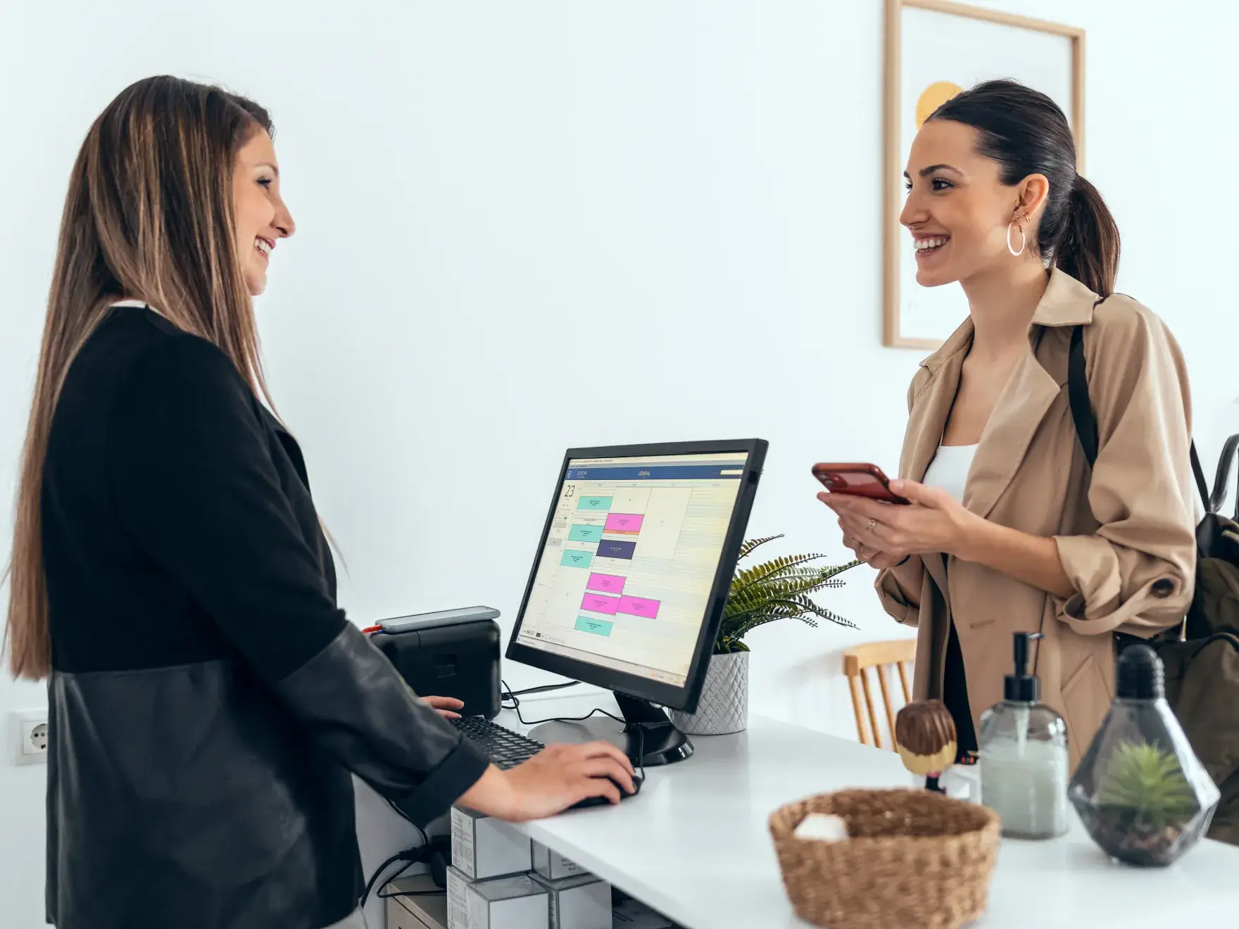 Two women standing in front of a computer screen.