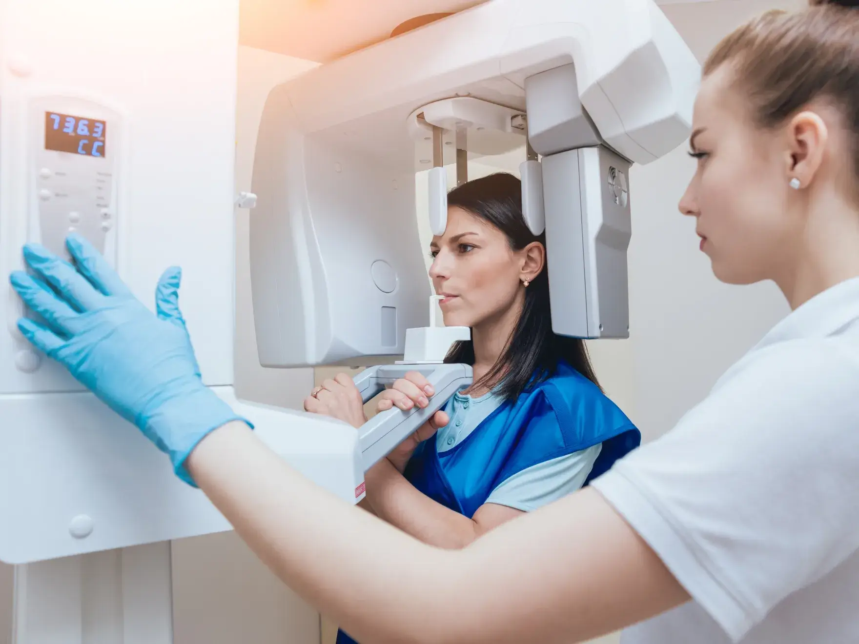 A woman in a white shirt and blue gloves working on a machine.