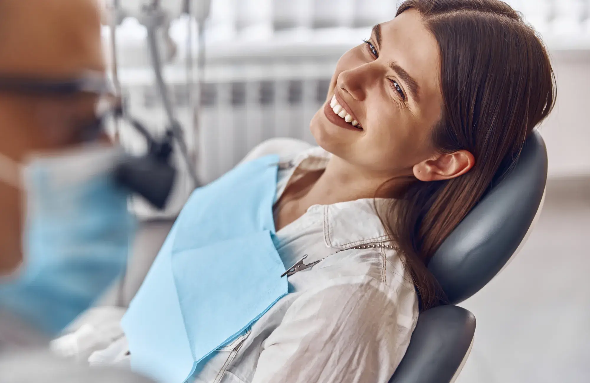 A woman sitting in a dentist chair smiling.