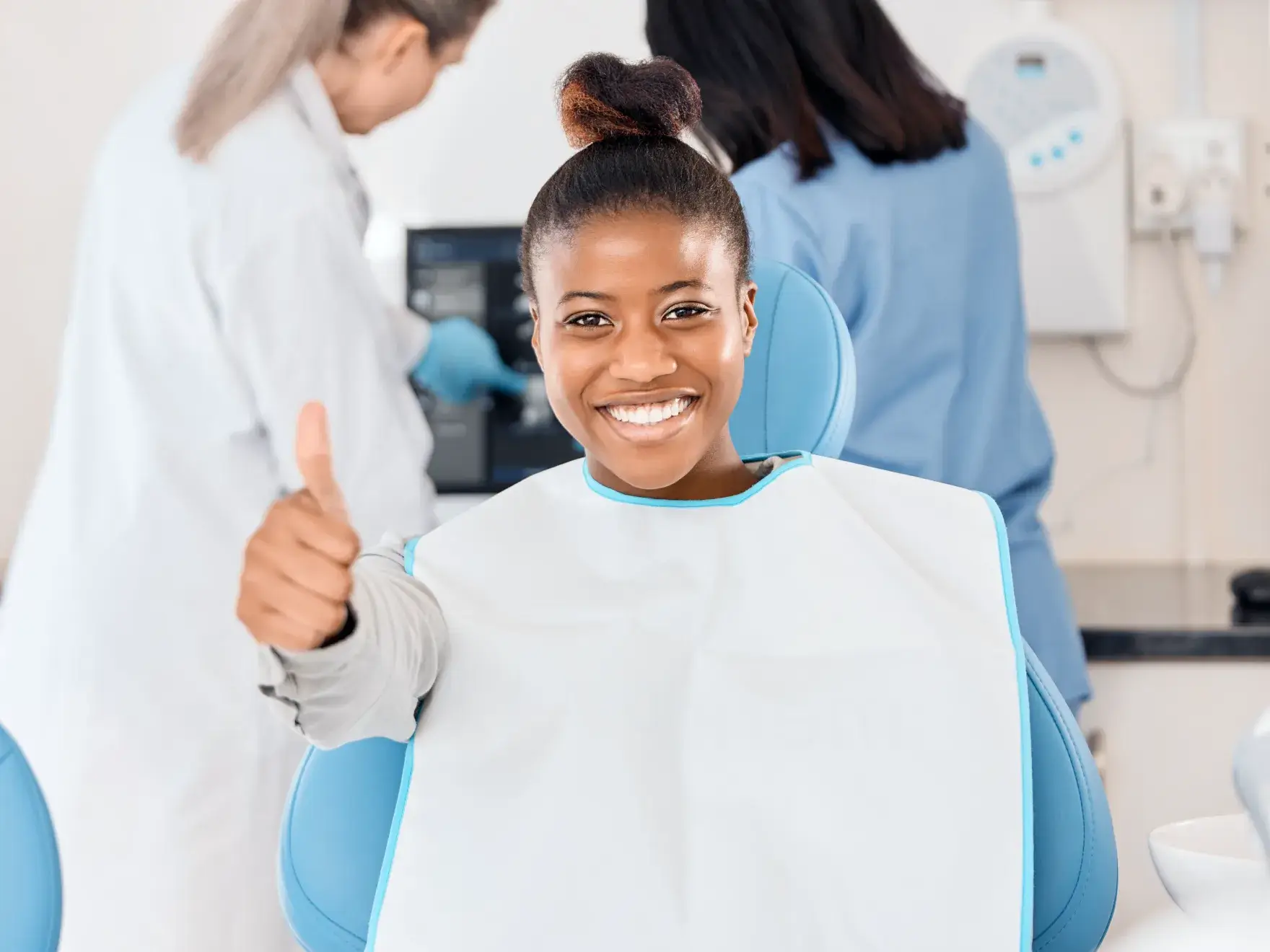 A woman in a chair giving a thumbs up.