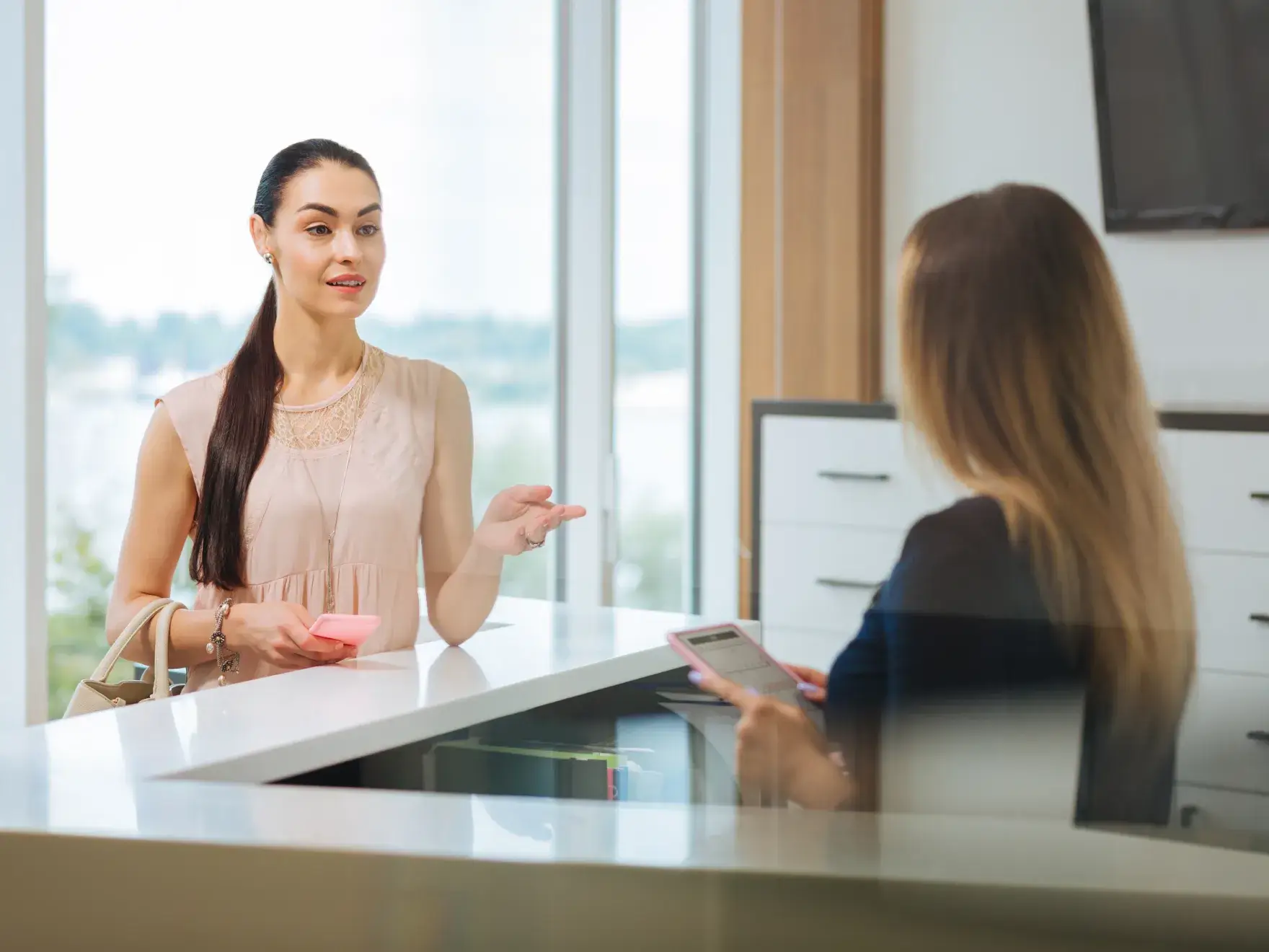 A woman sitting at a desk talking to another woman.