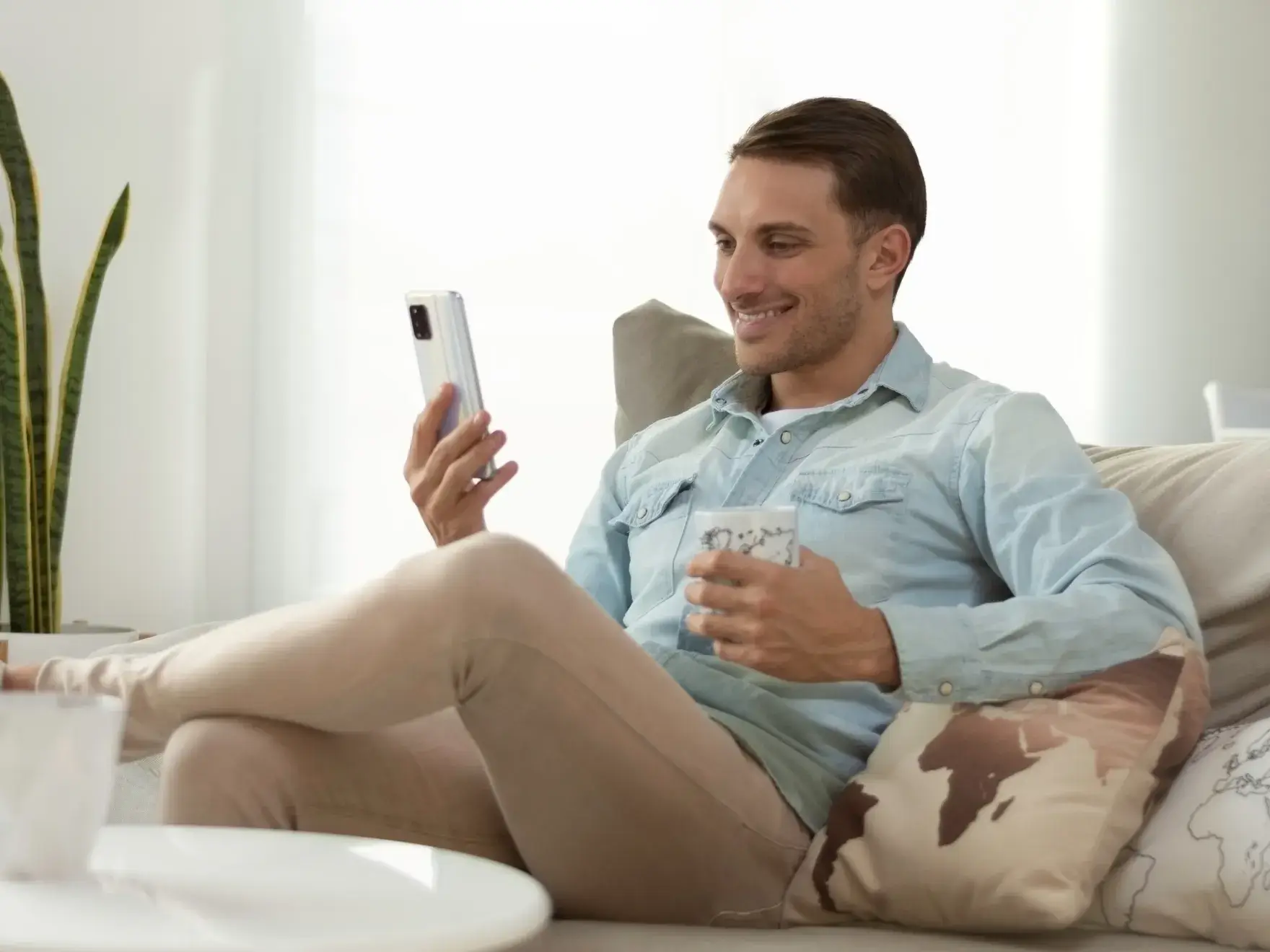 A man sitting on a couch holding a cell phone.