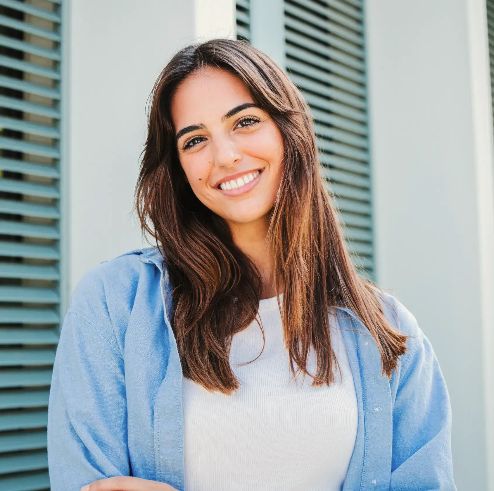 A woman standing in front of a window with shutters.