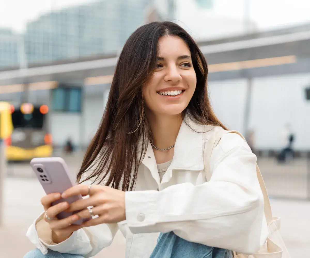 A woman sitting on the ground holding a cell phone.