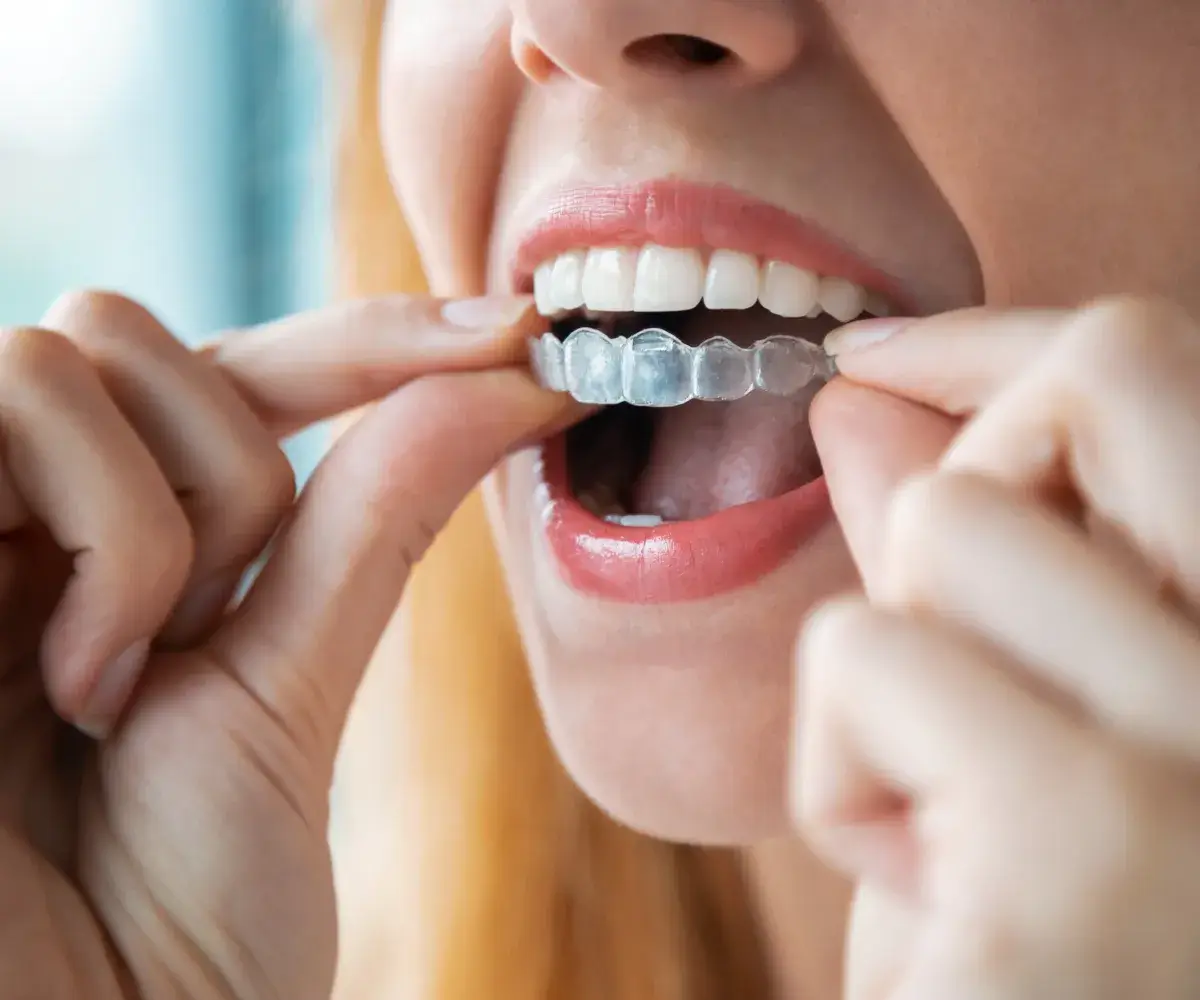 A woman brushing her teeth with a toothbrush.