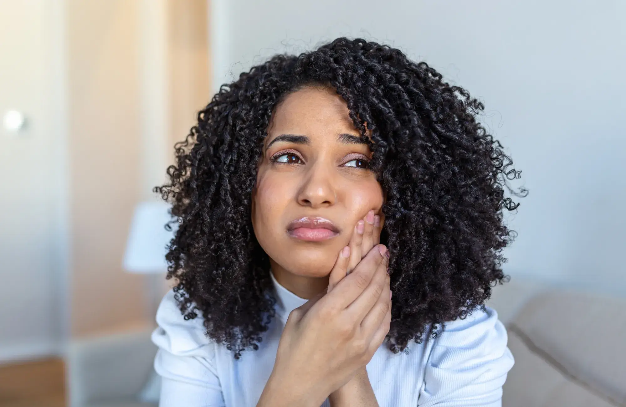 A woman with curly hair sitting on a couch.